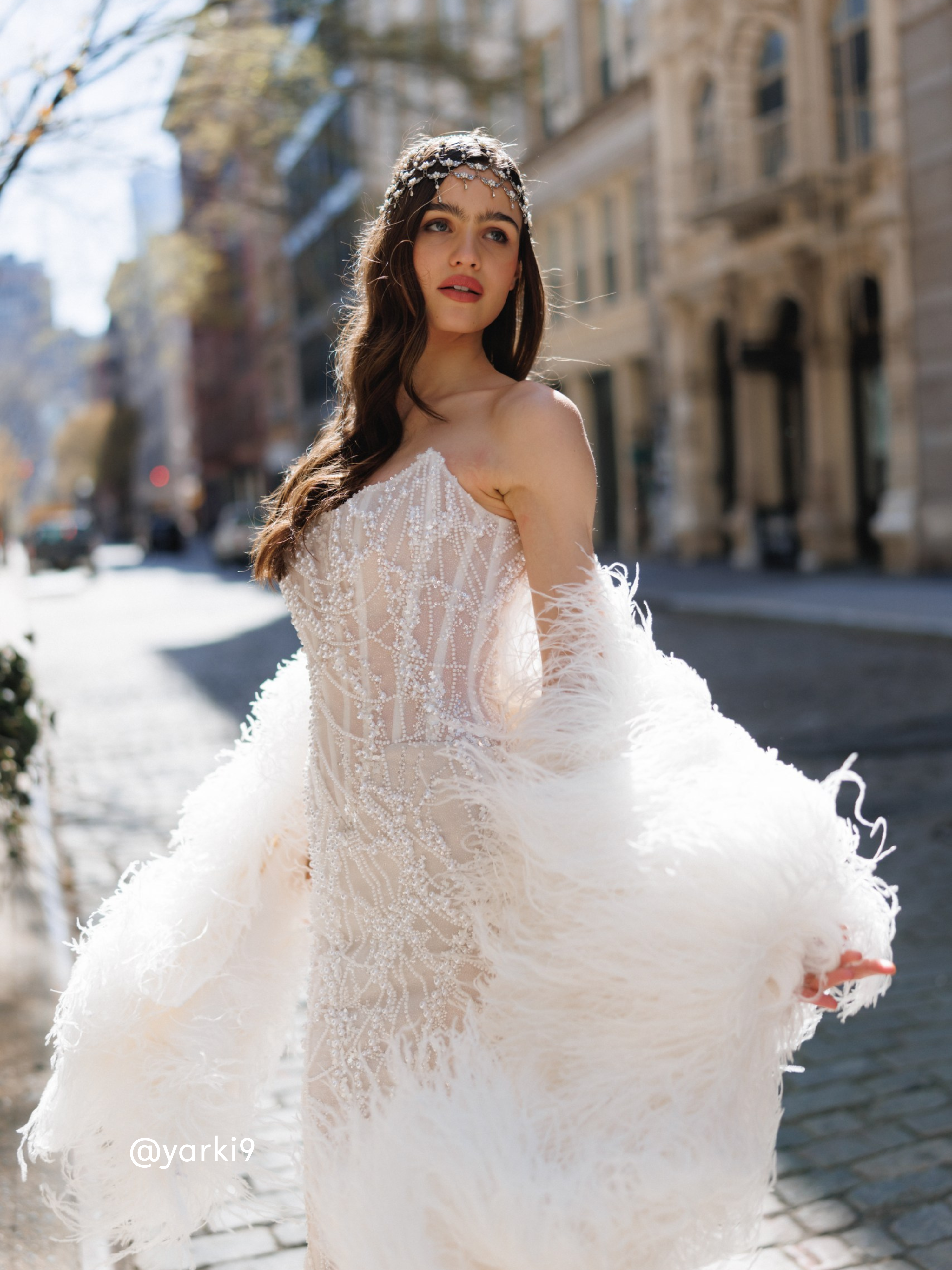 Woman in a white wedding dress standing on a city street.