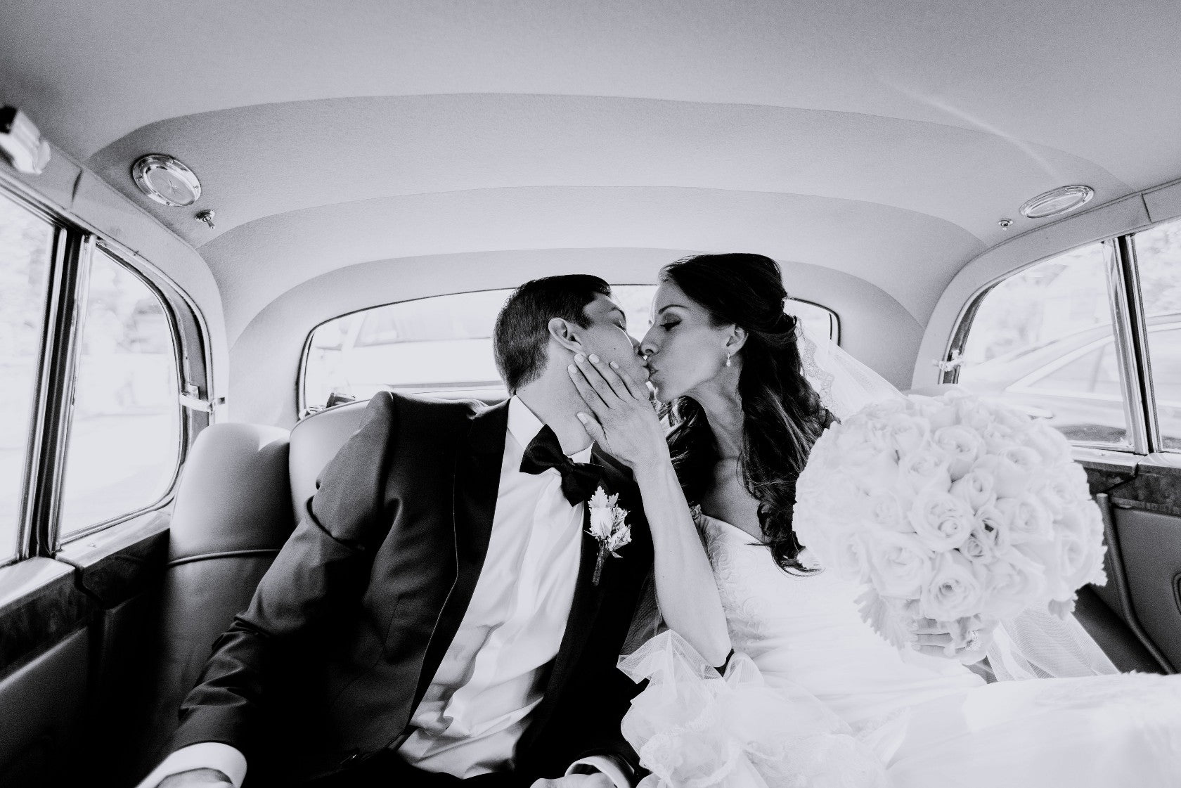 GL Bride wearing our Fiona gown sitting in a car kissing her husband
