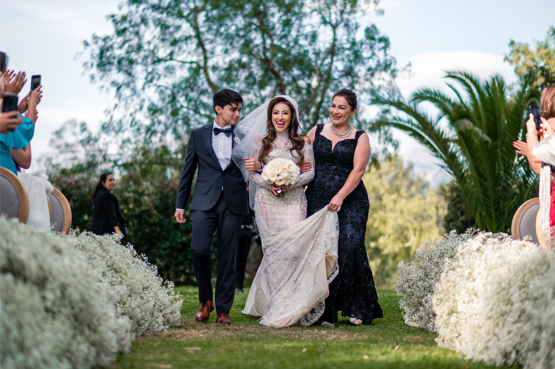 GL Bride Betty Luna in our Élysée walking down the aisle filled with baby's breath flowers