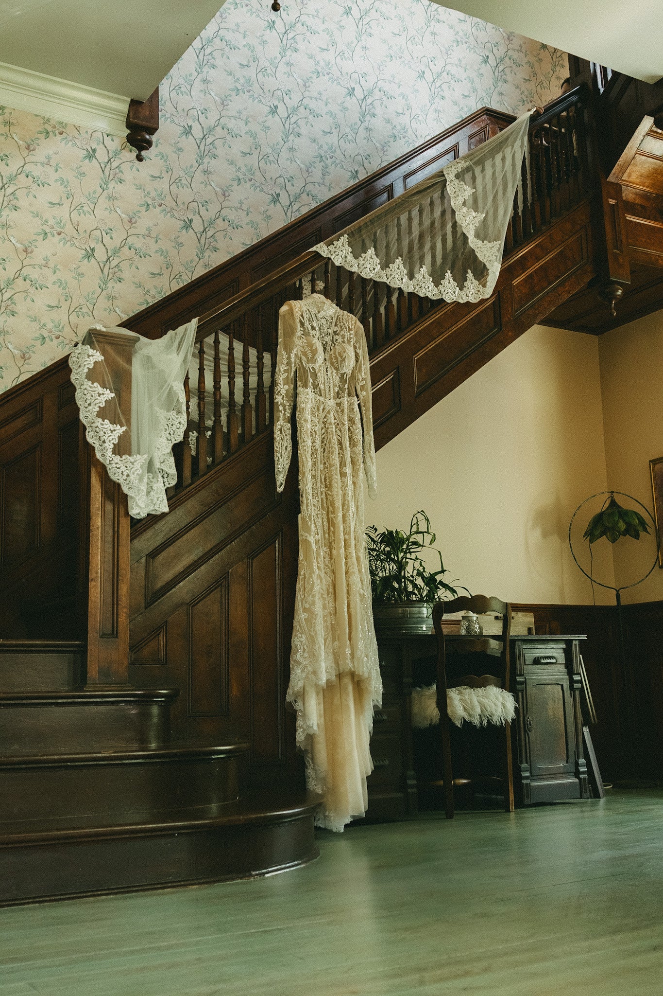 Vintage wedding dress hanging on a wooden staircase with lace decorations.