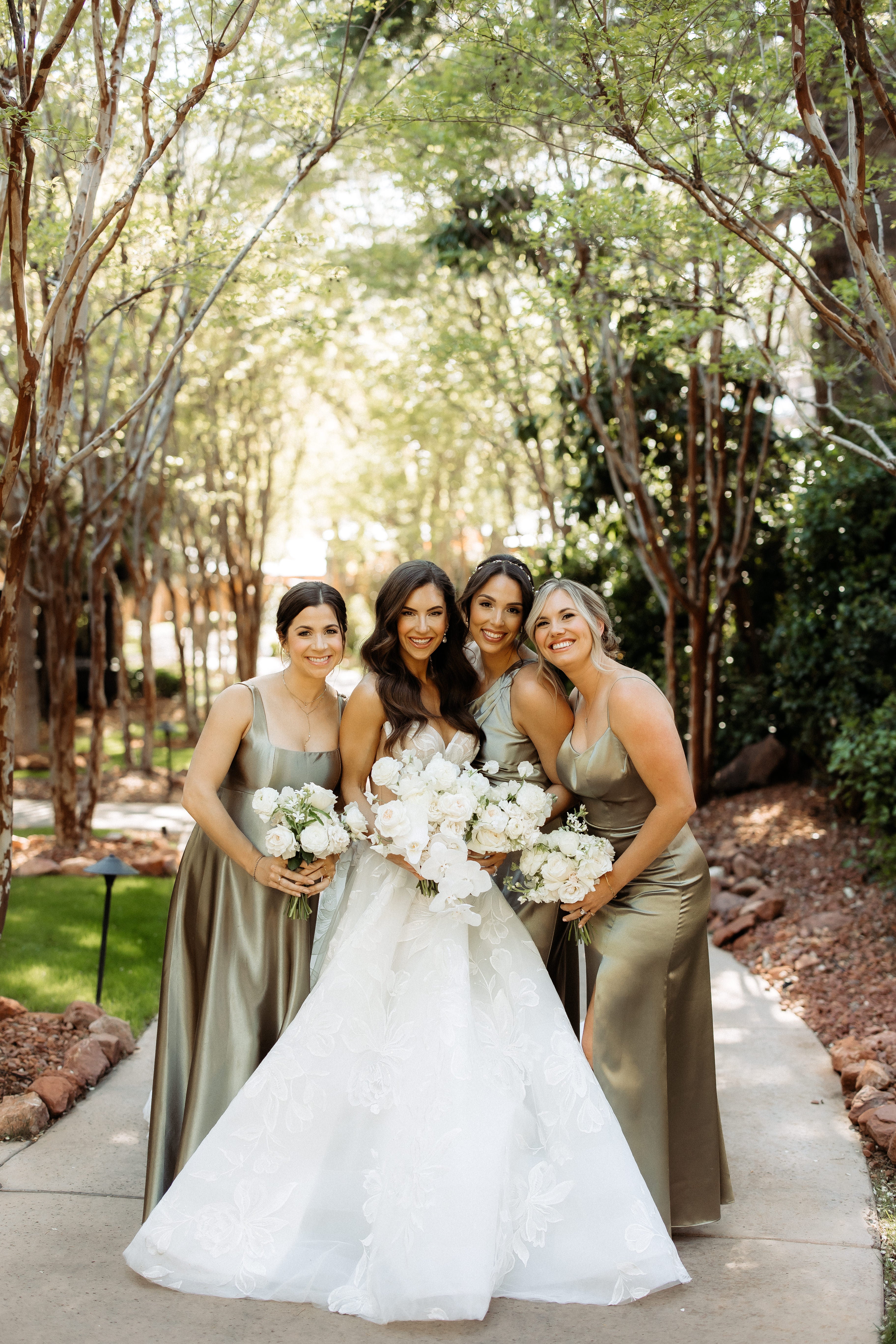 Bride and bridesmaids posing outdoors with trees in the background