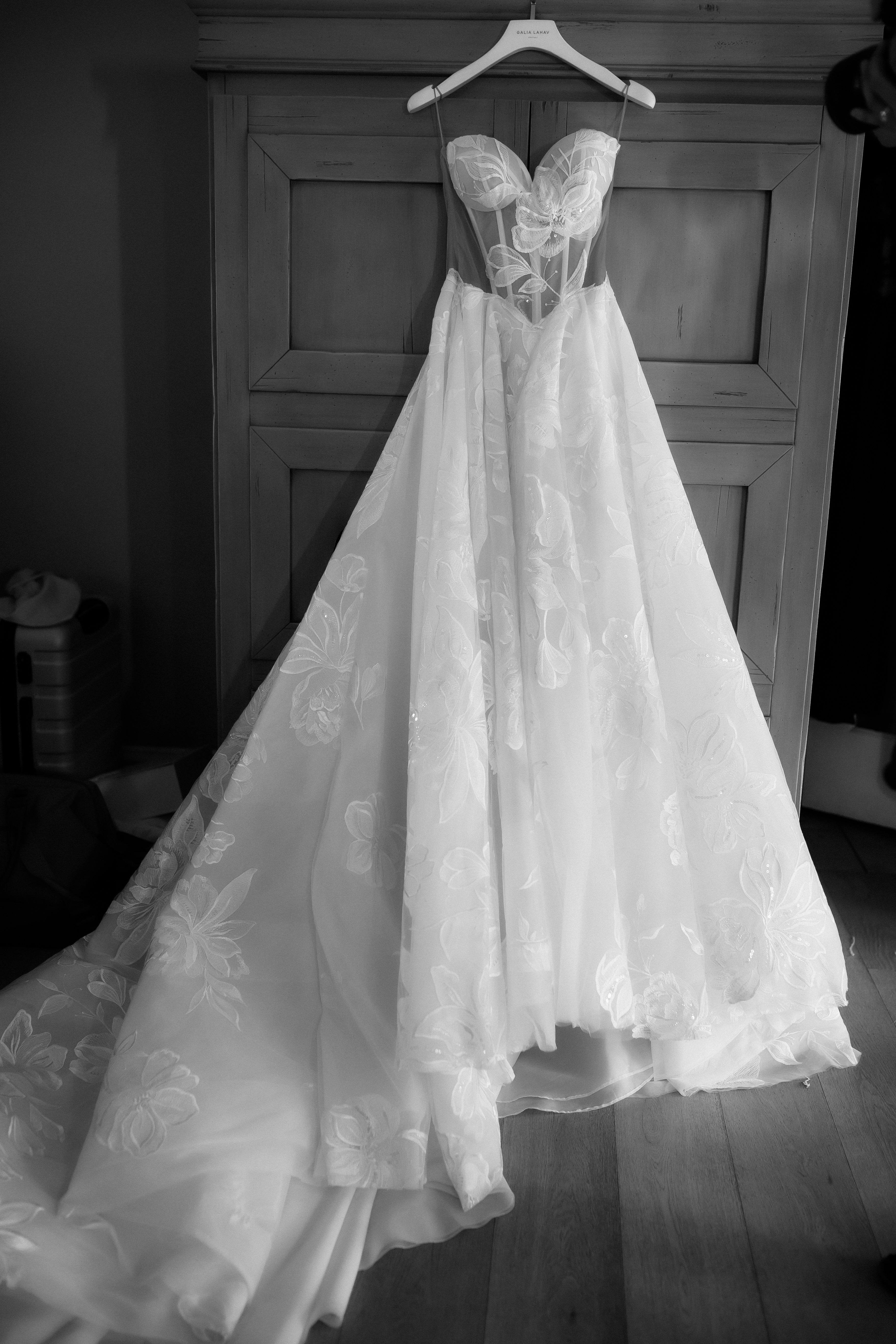Evelyn wedding dress with lace details hanging on a wooden door.