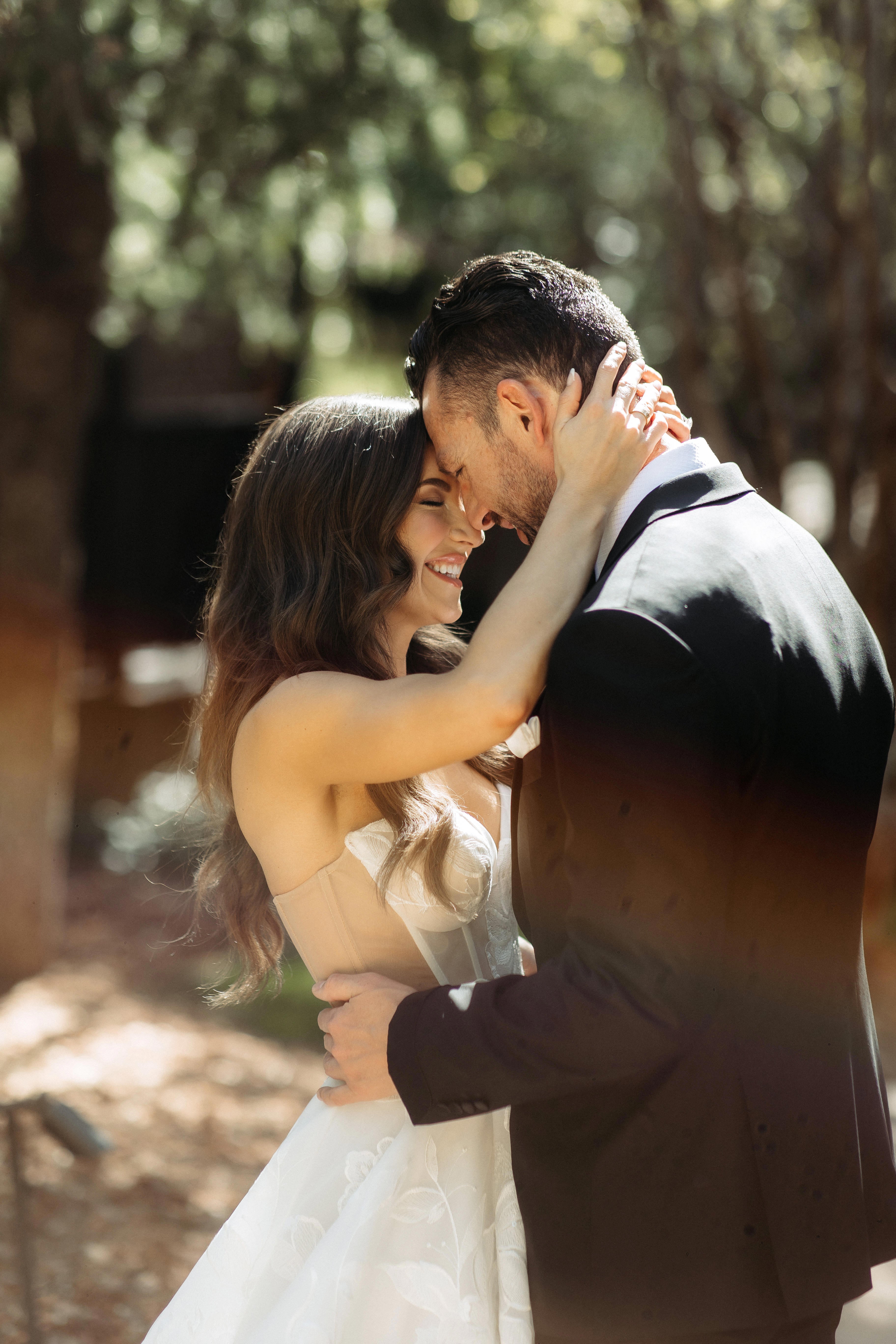 Couple embracing outdoors with a natural background. Bride wearing Galia Lahav Evelyn dress