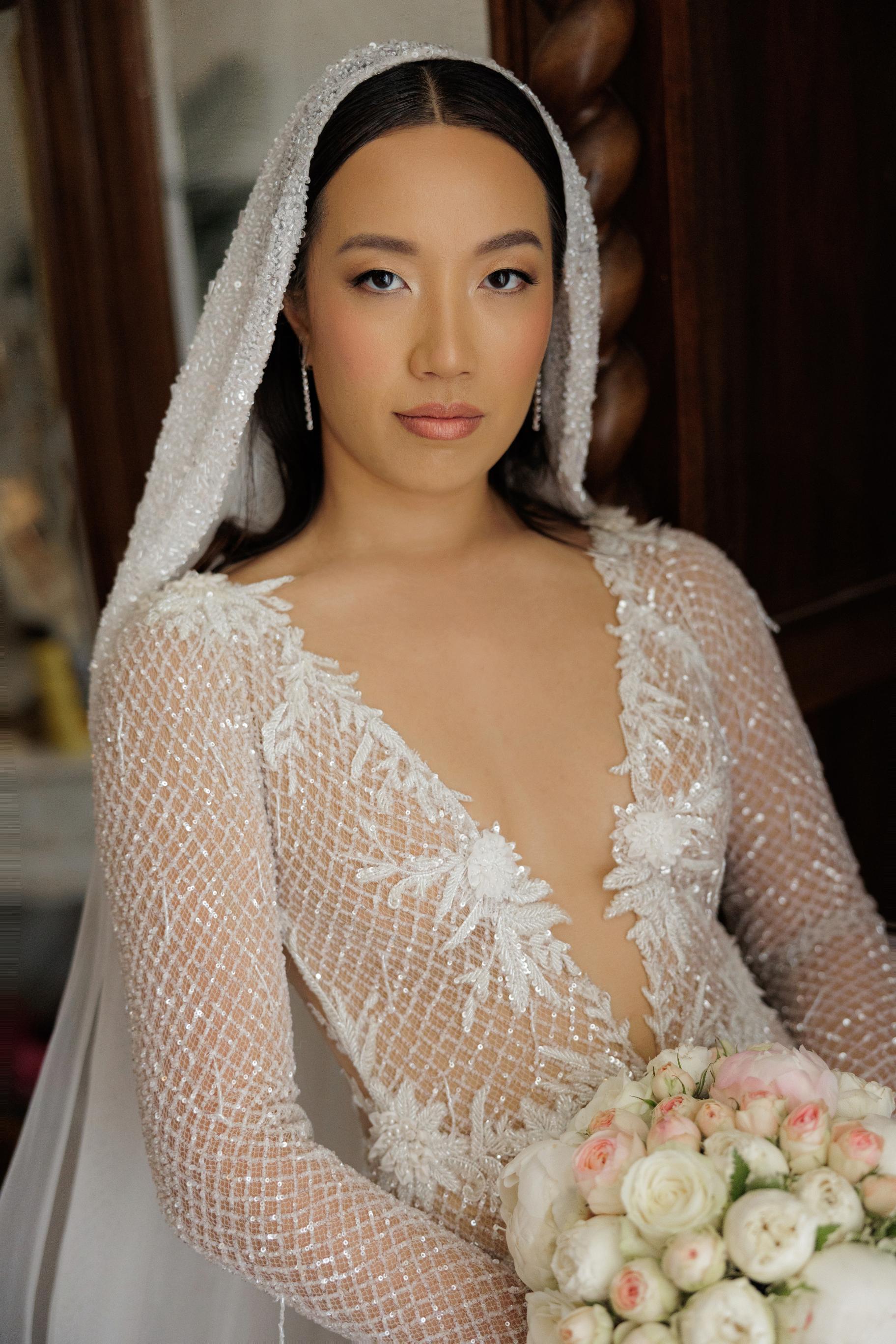 Woman in a wedding dress with a veil holding flowers indoors.