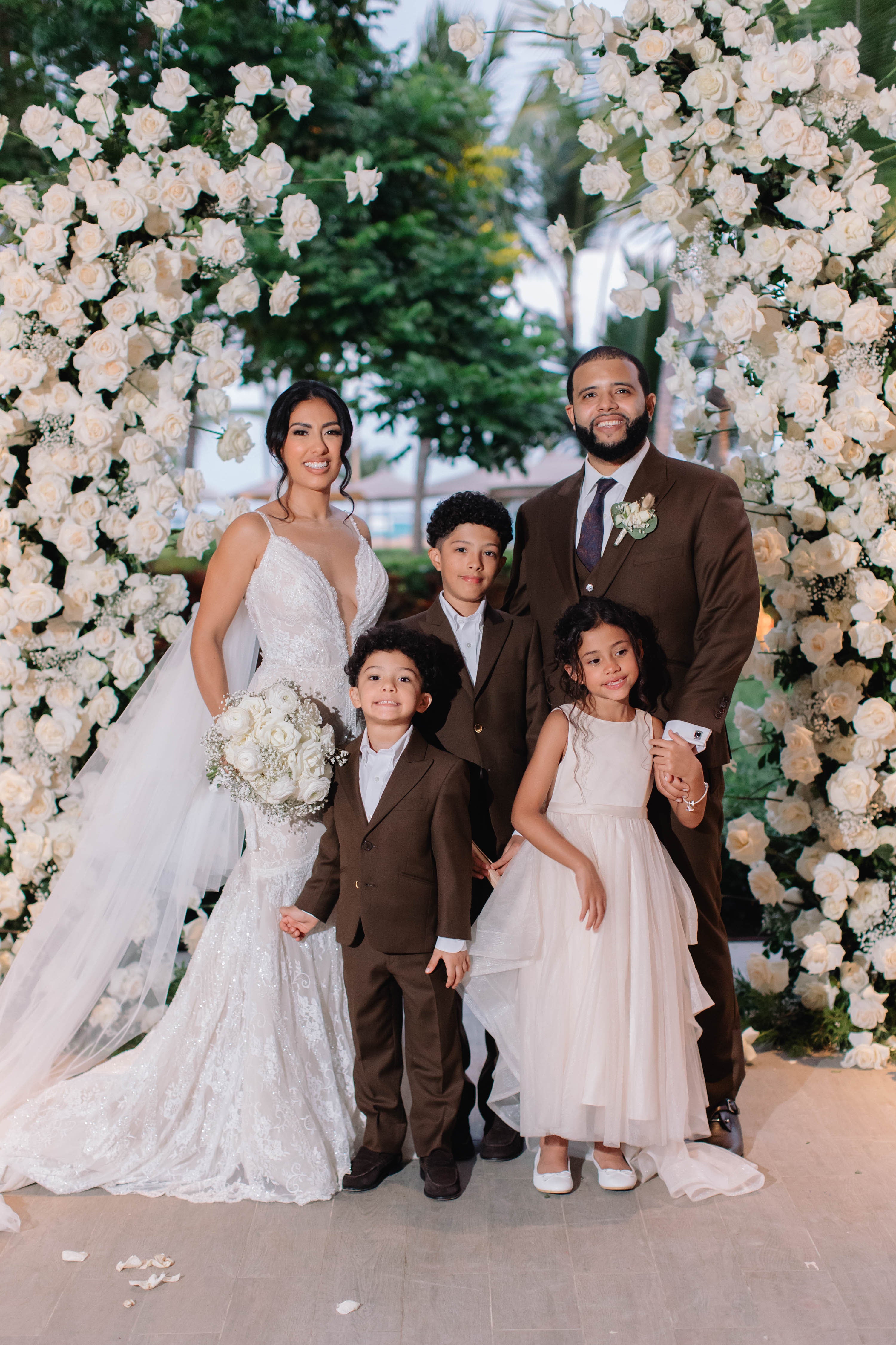 Family of five posing in front of a floral archway