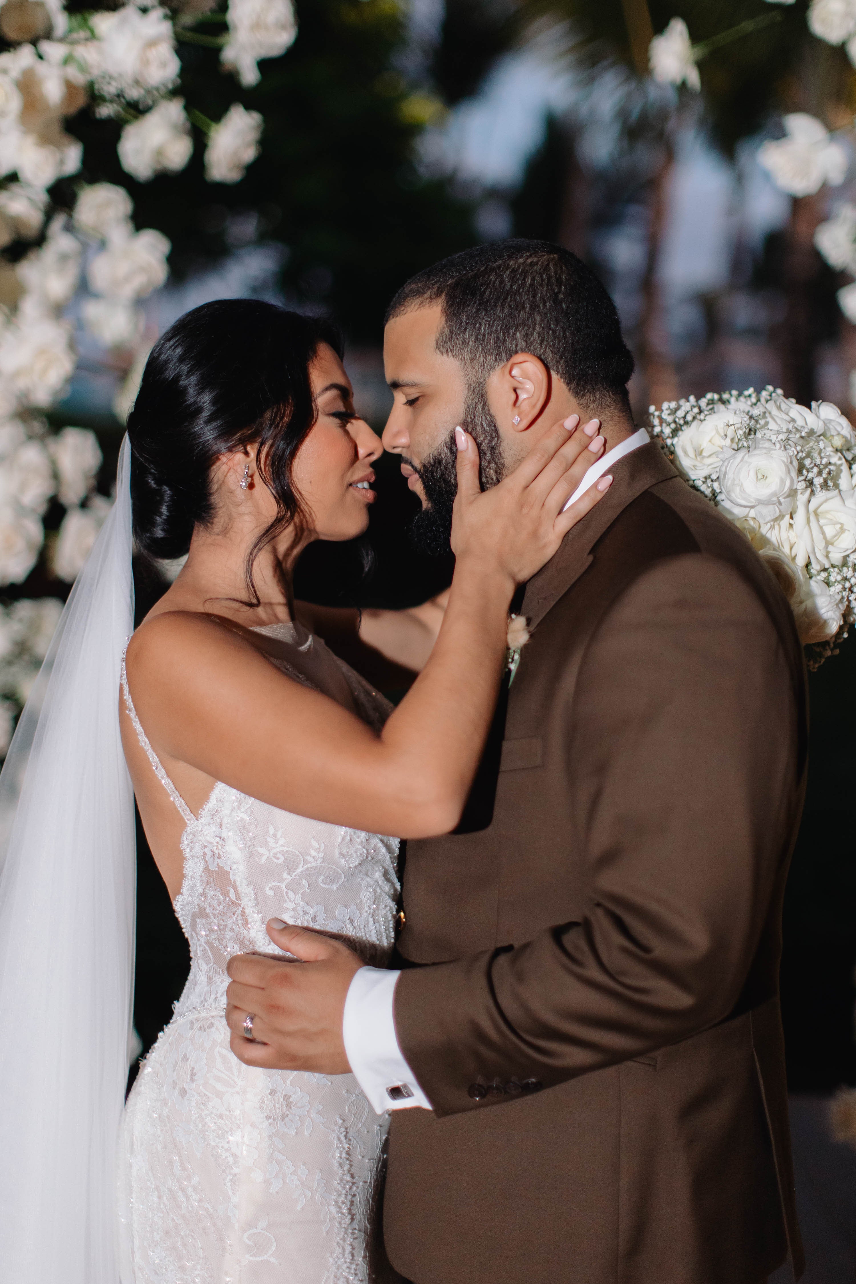 Couple embracing in a wedding setting with floral decorations.