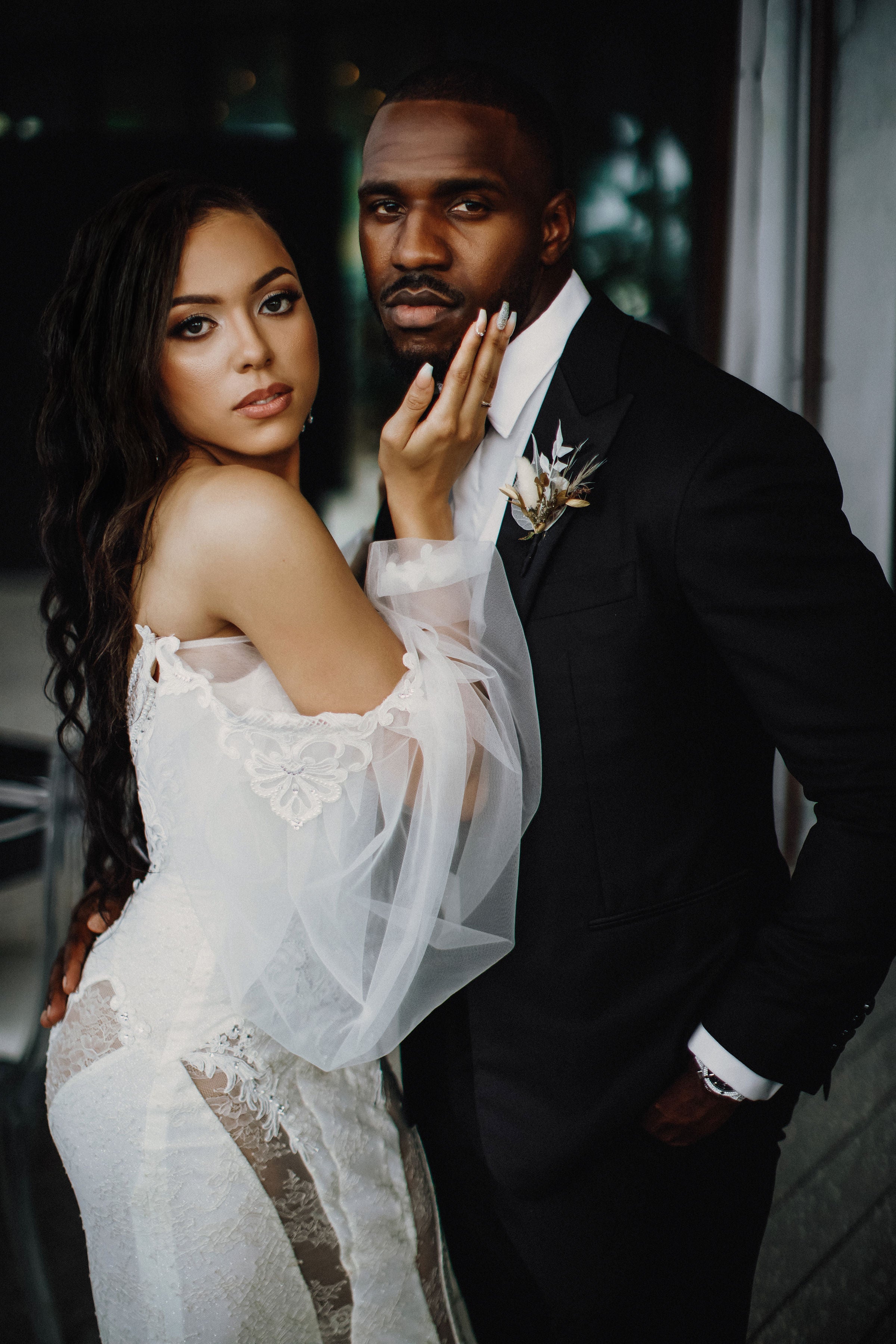 The couple embracing with the bride wearing our Thelma gown and the groom in formal attire
