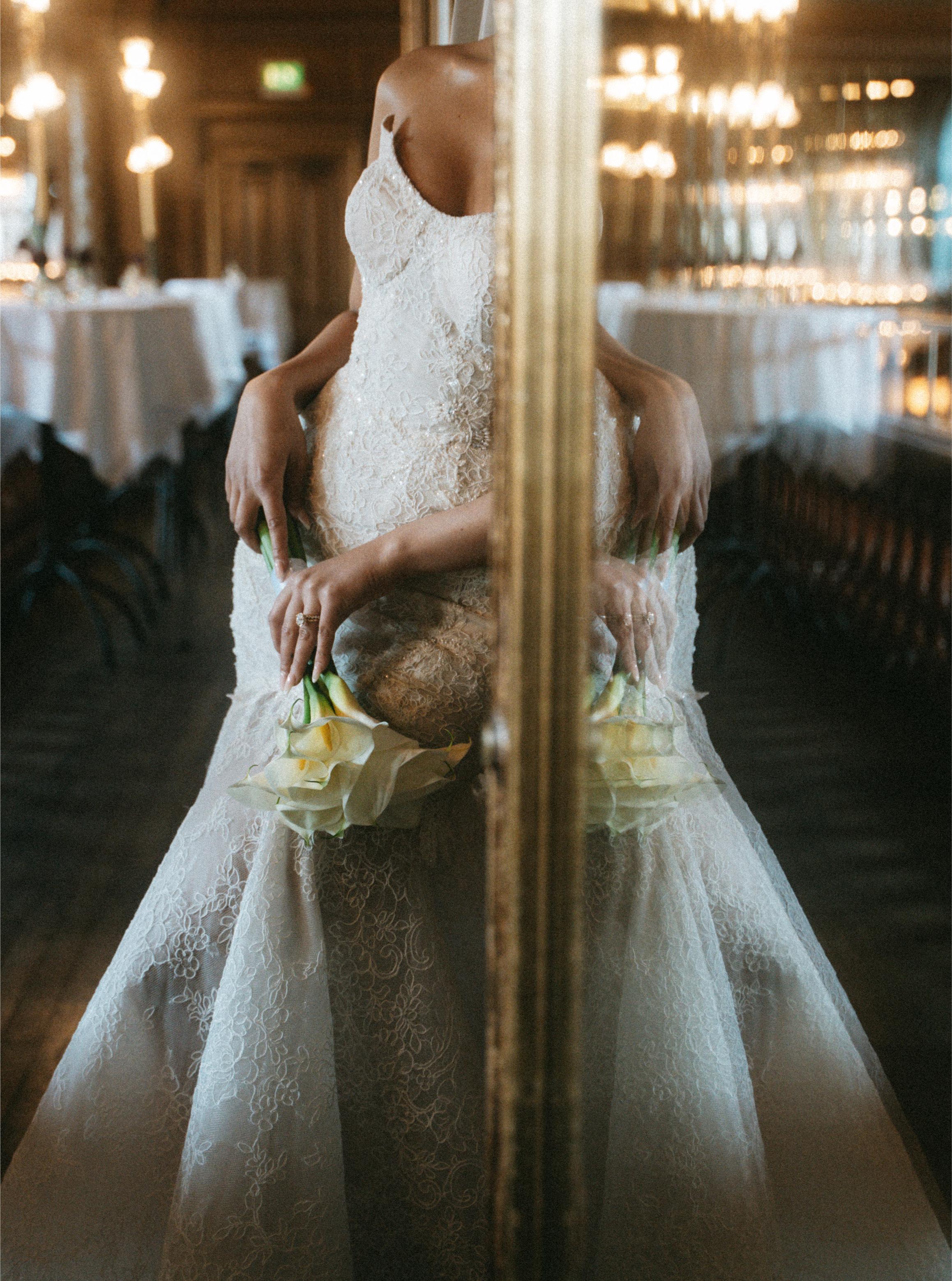 Person wearing a white lace wedding dress holding a bouquet in a decorated indoor setting.