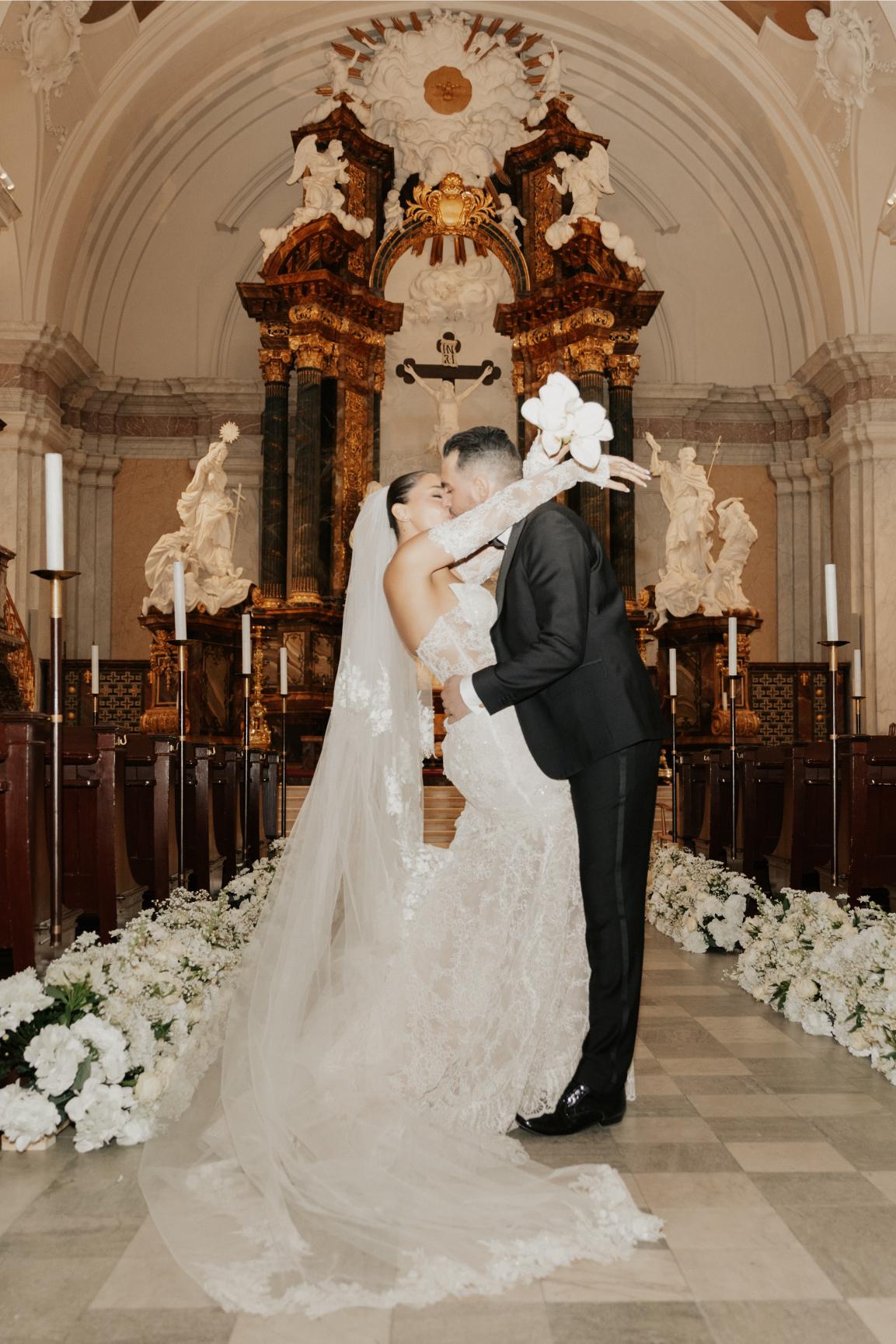 Wedding couple embracing in a church with floral decorations.