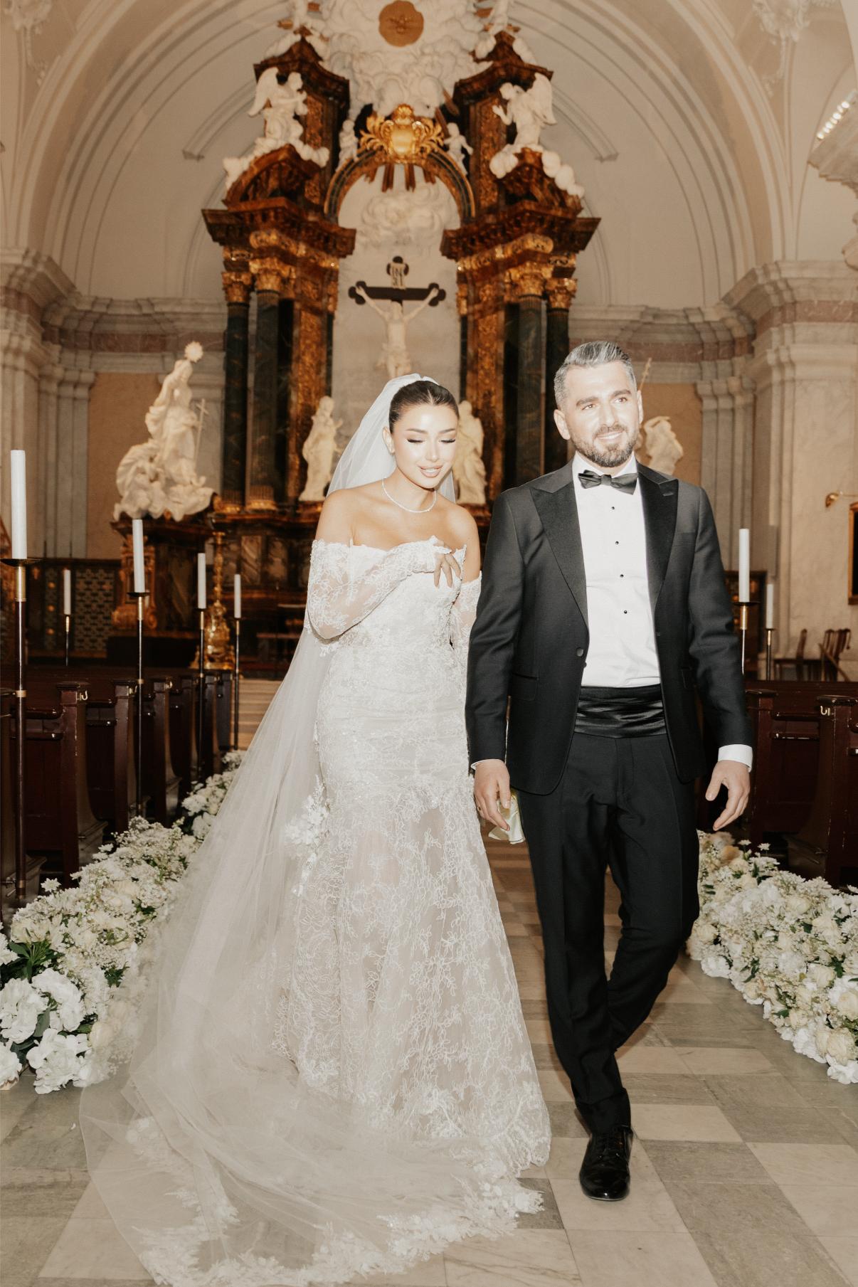Wedding couple walking down an aisle in a decorated church.