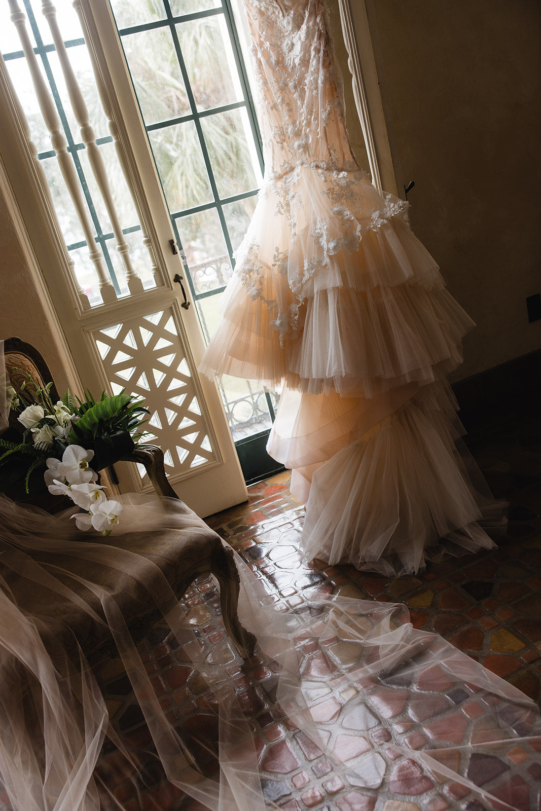 Galia Lahav Veronica gown on a mannequin in a room with a decorative door and flowers.