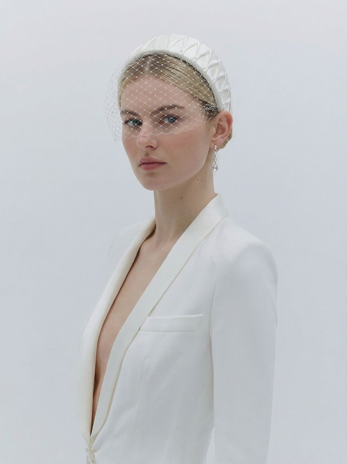 Woman wearing a white blazer with a deep neckline against a plain background