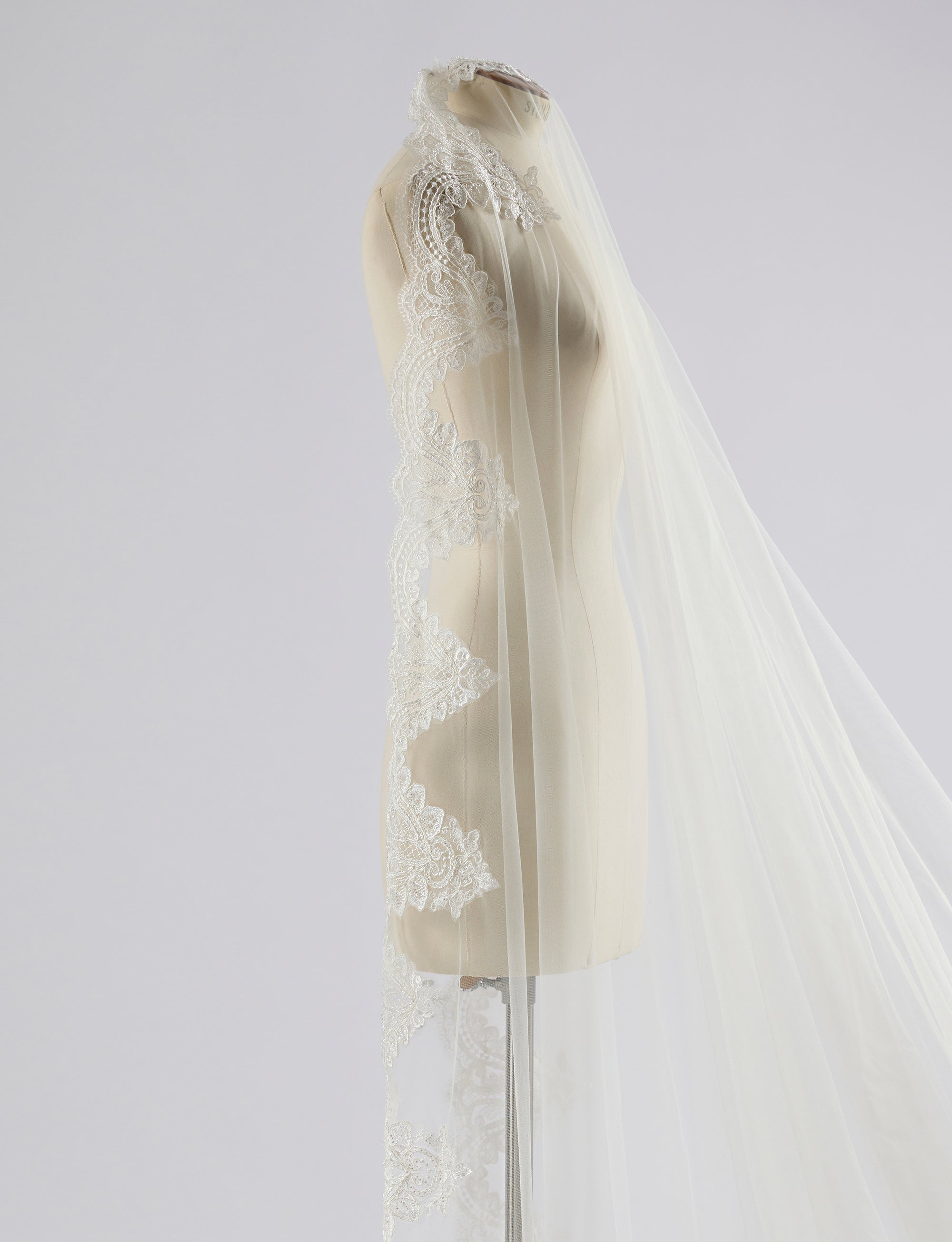 White lace veil on a mannequin against a light gray background