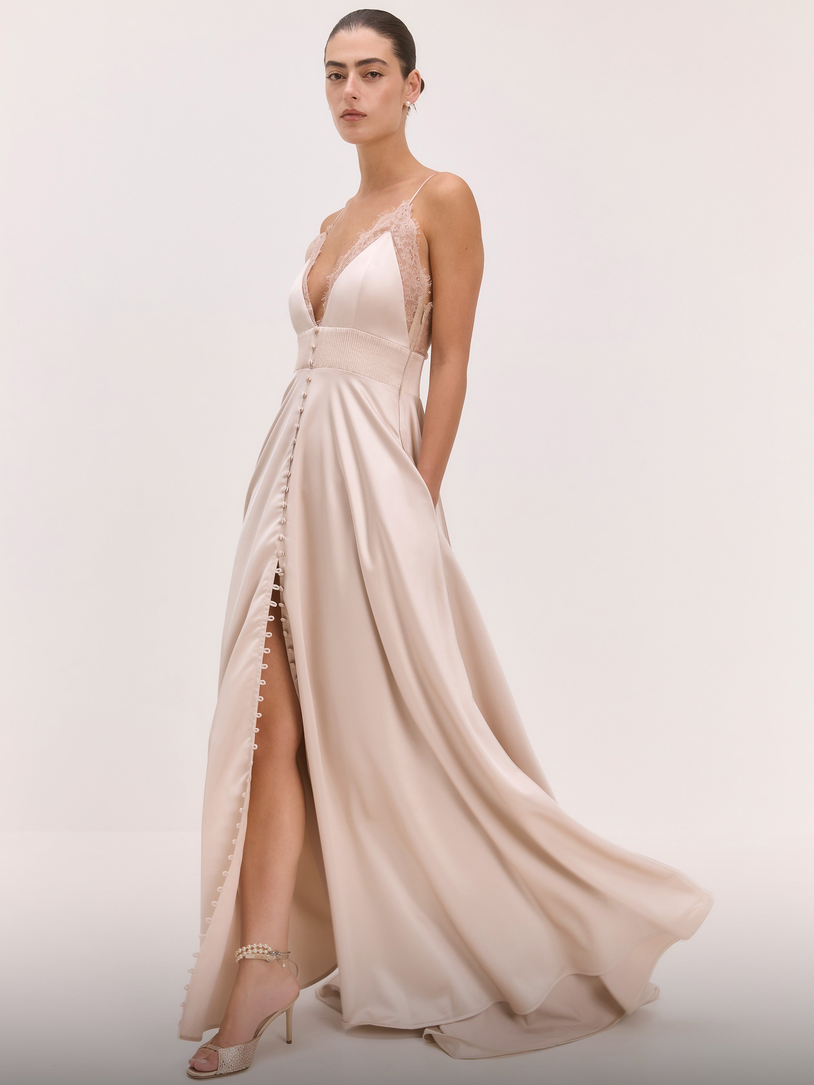 Woman wearing a flowing beige dress on a plain background