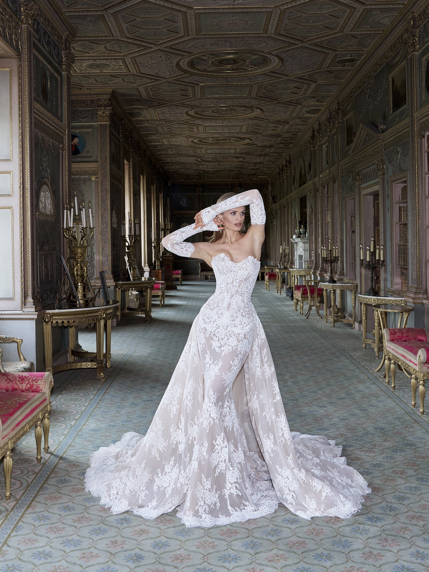 Woman in a white wedding dress standing in an elegant hallway with ornate decorations.