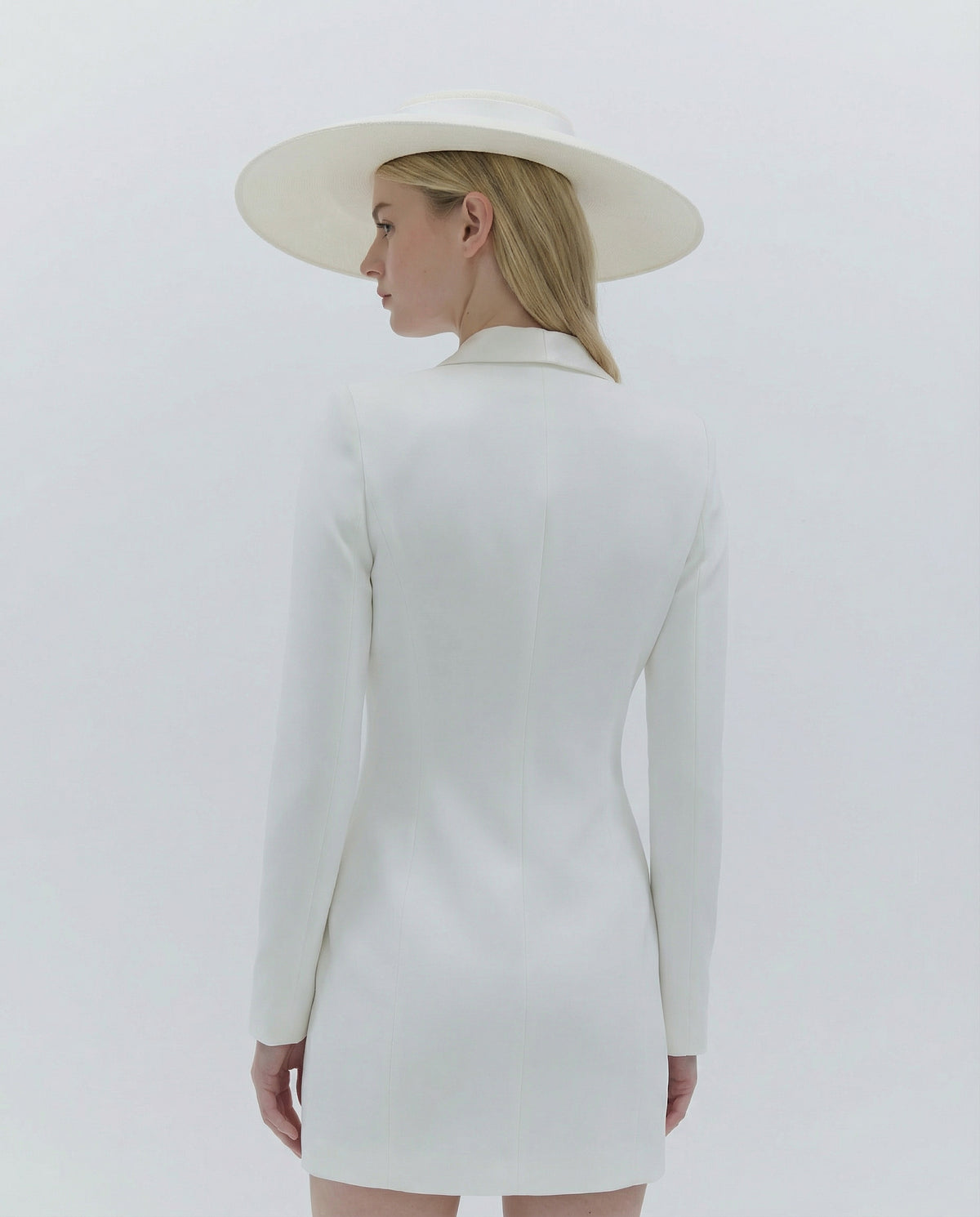 Person wearing a white dress and hat against a light gray background