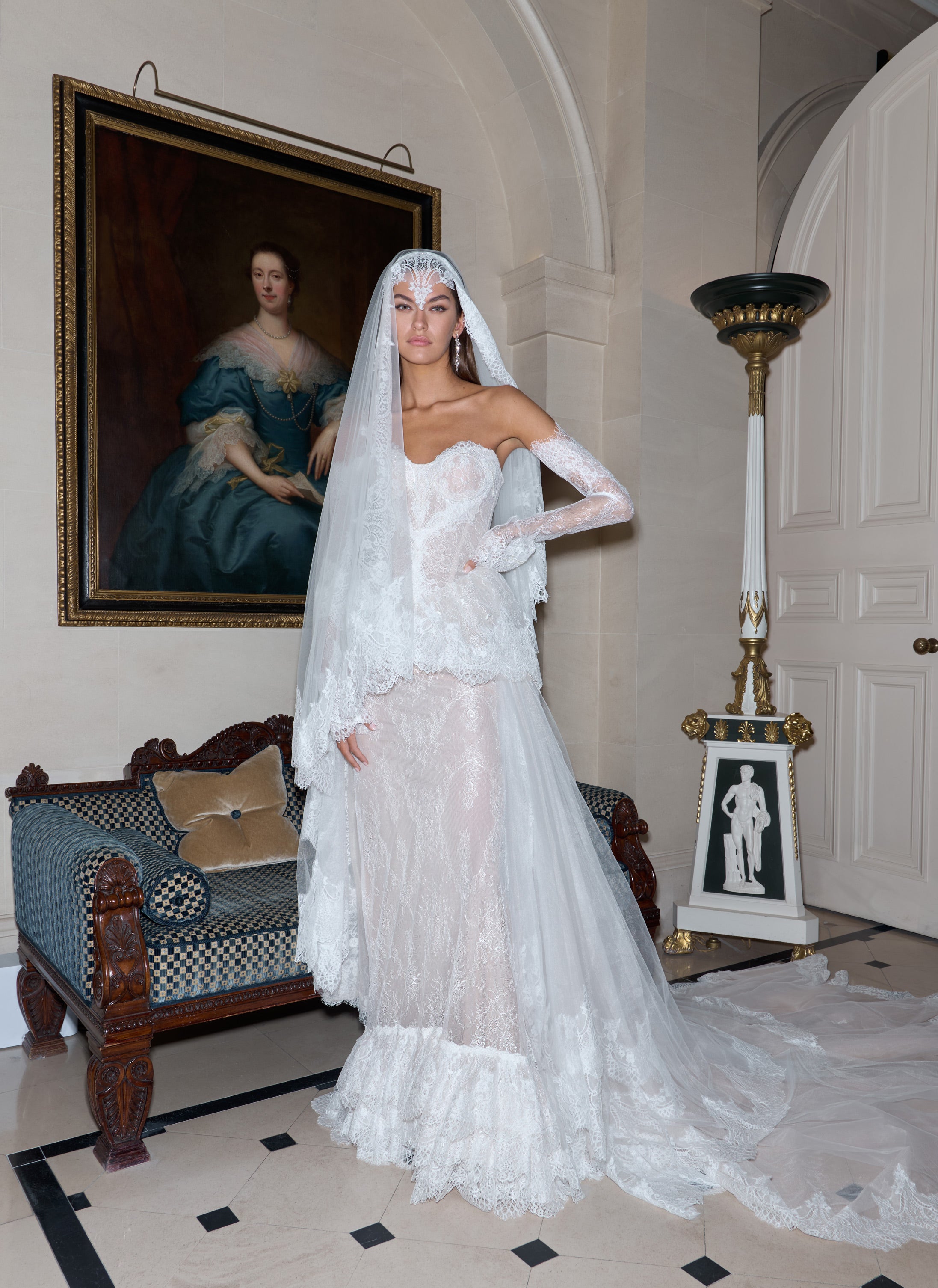 Woman in a white wedding dress with a long train standing in an elegant room.