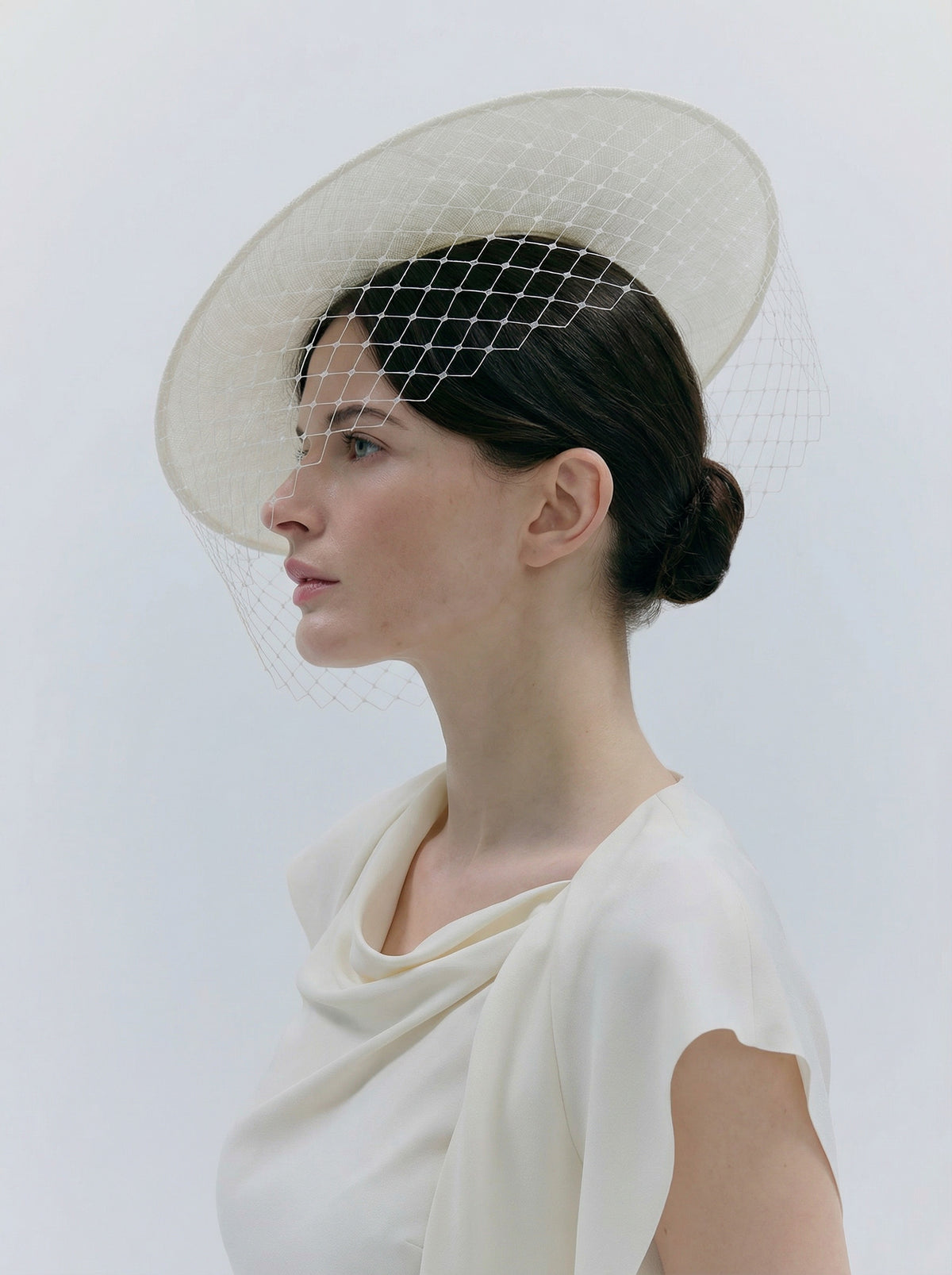 Woman wearing a white dress and a decorative headpiece against a light background