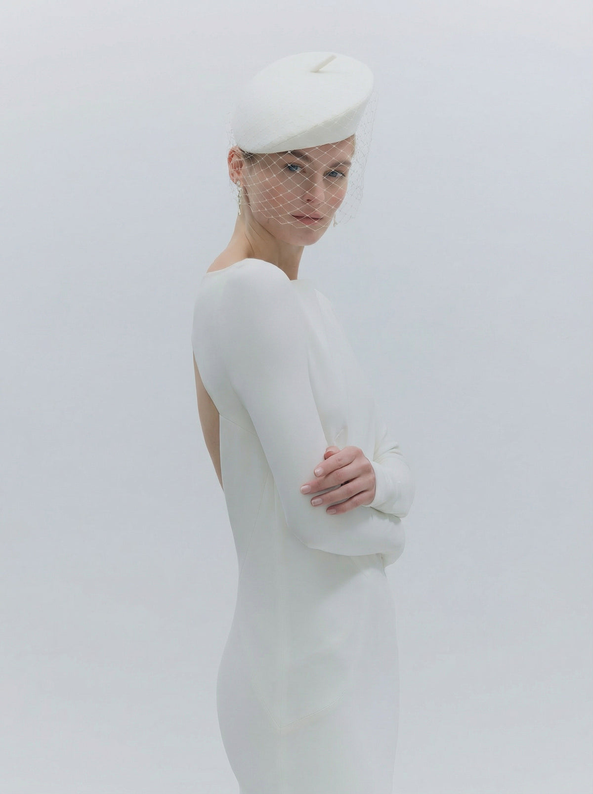 Woman wearing a white dress and hat against a plain background