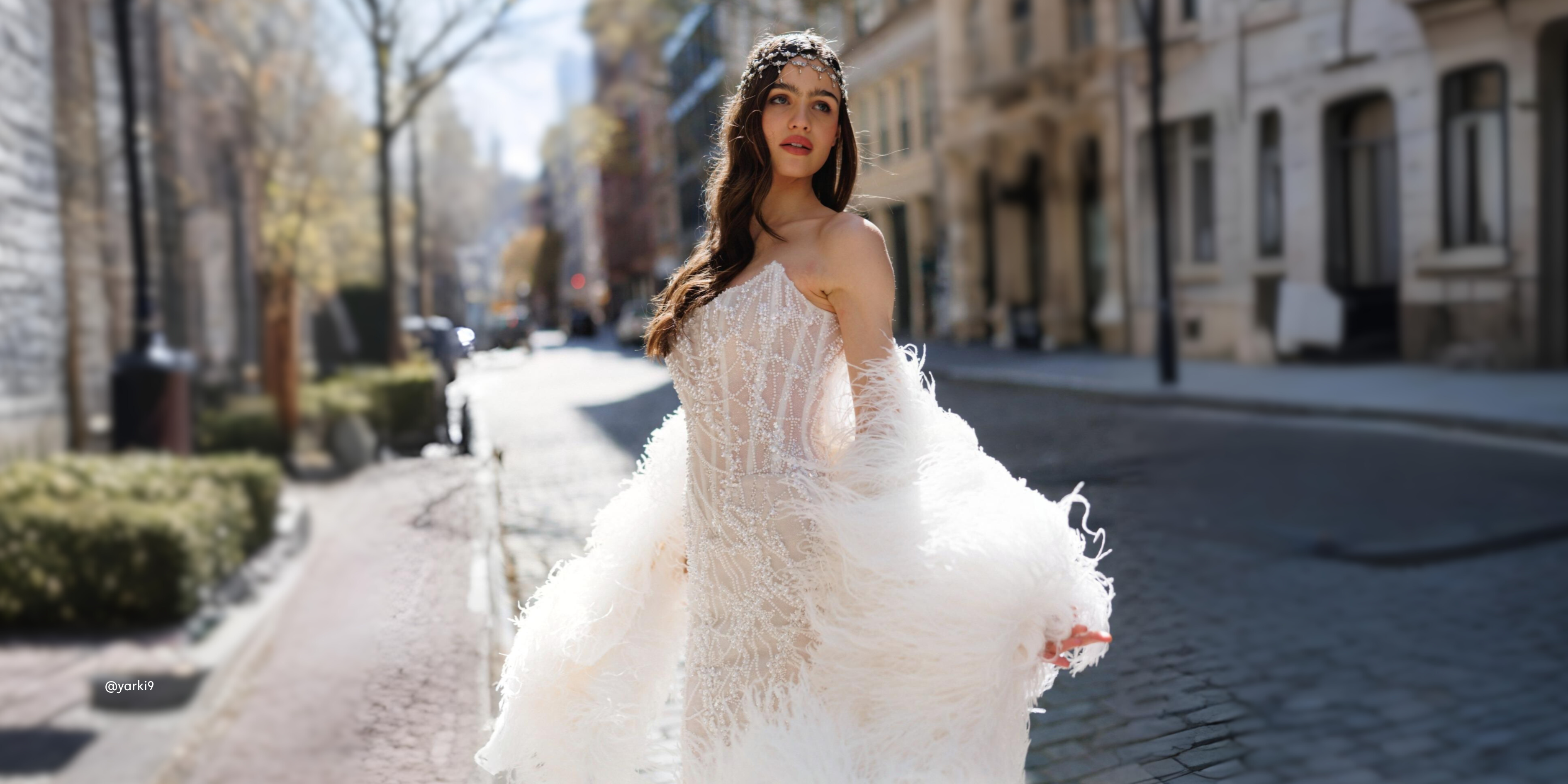Woman in a white wedding dress standing on a city street.
