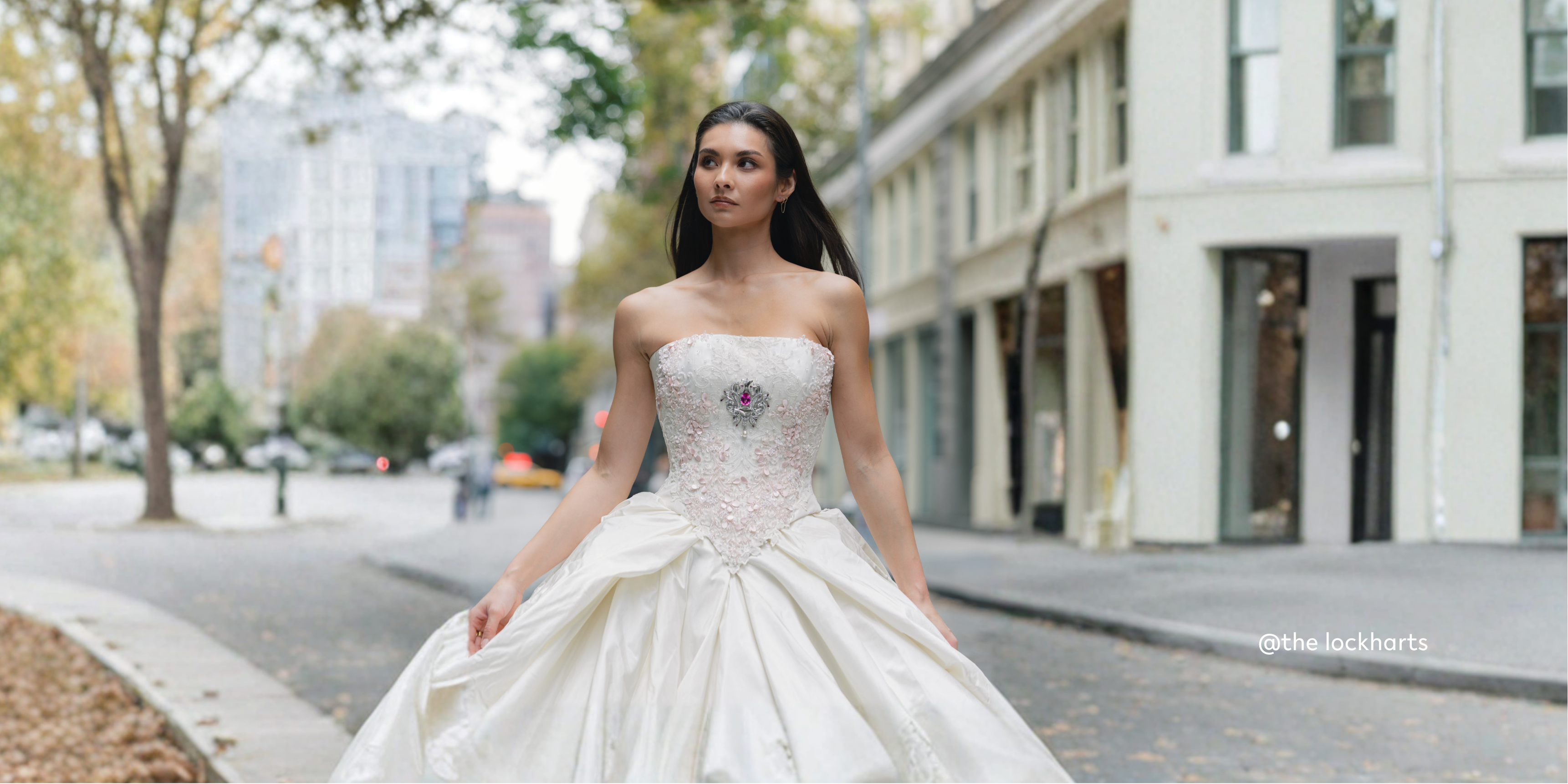 Woman in a white wedding dress standing on a city street.