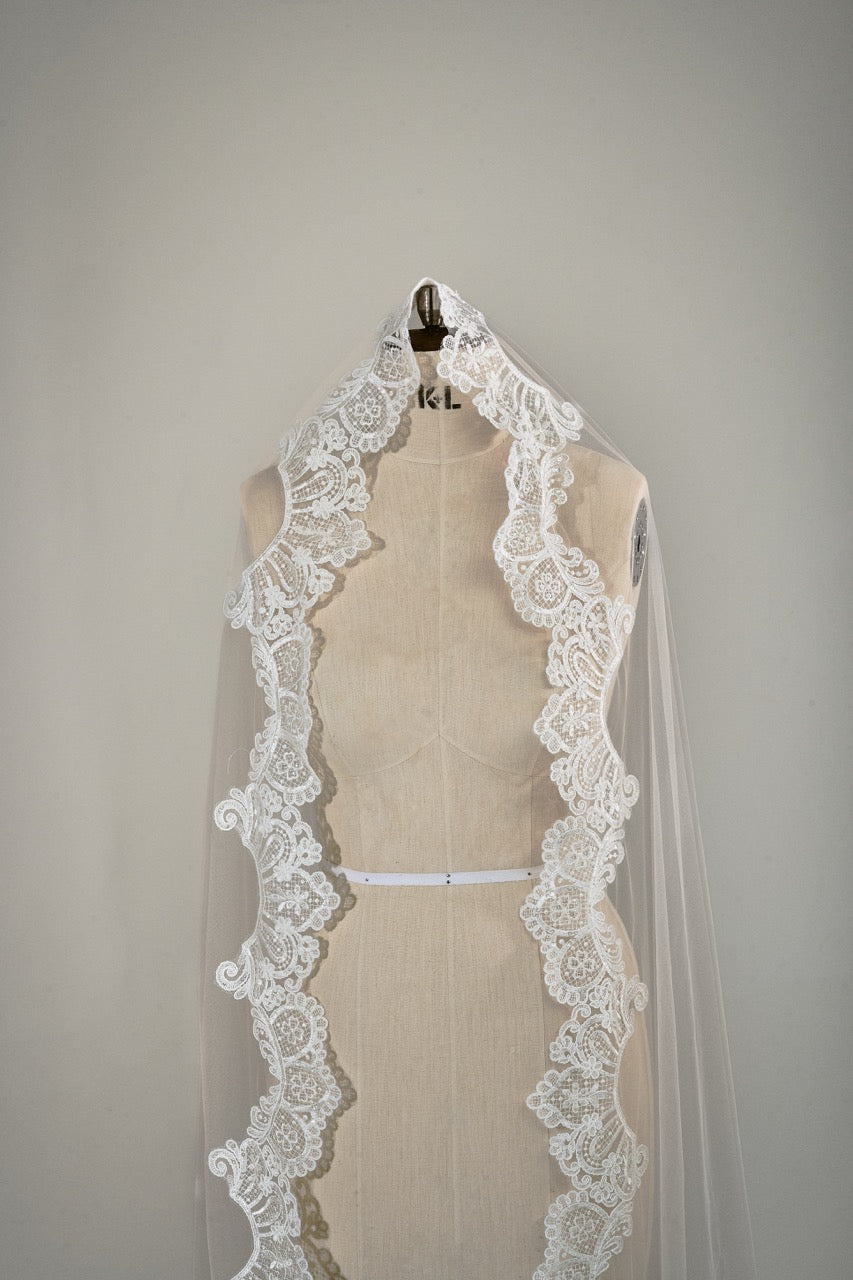 Lace wedding veil on a mannequin against a plain background