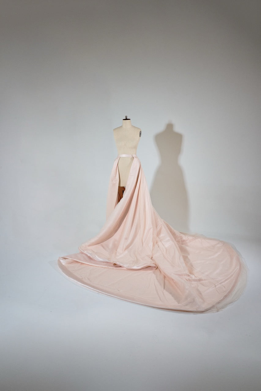 Pink evening gown on a mannequin against a plain background