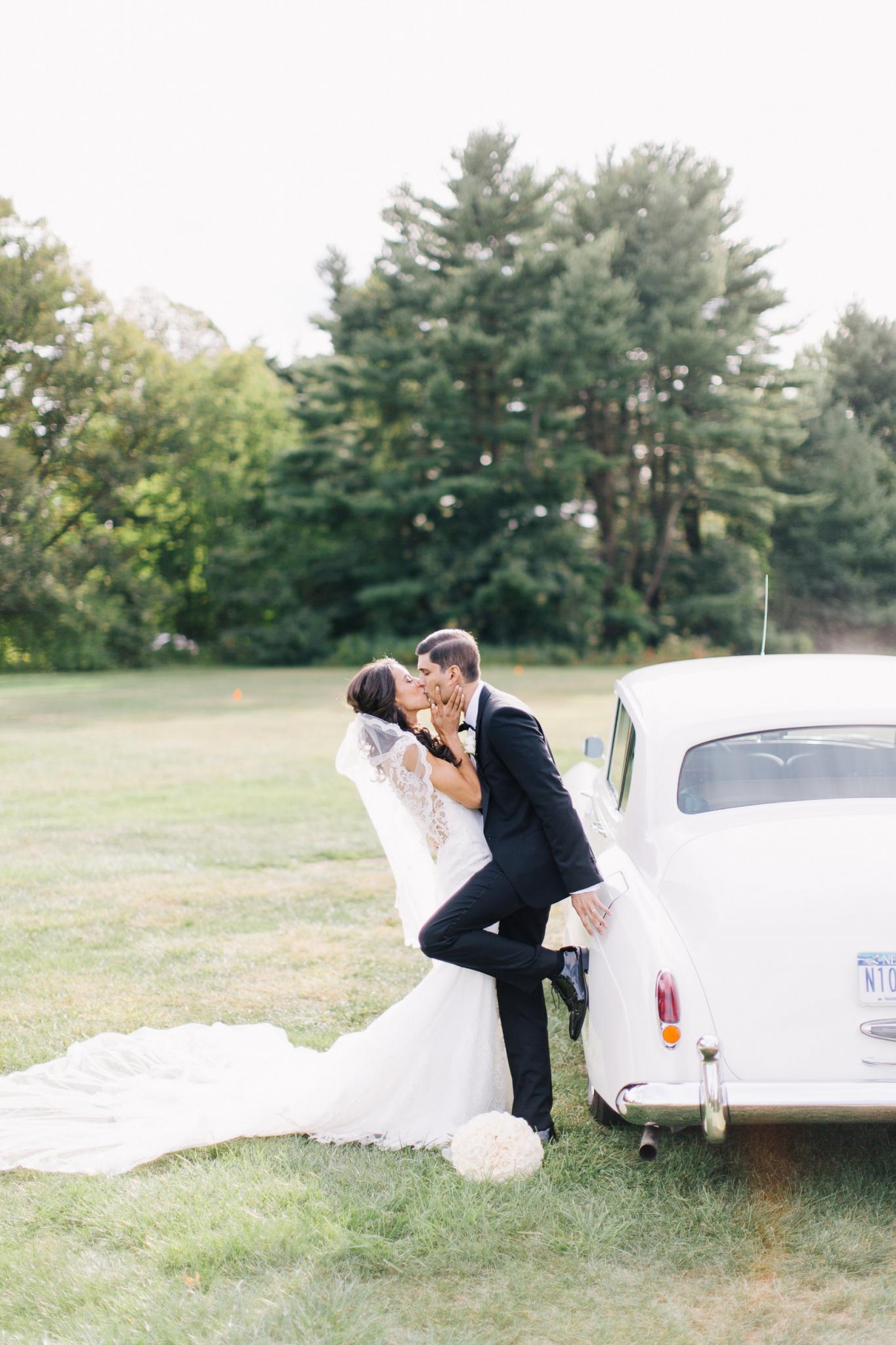 GL Bride Jennifer in our Fiona kissing her groom next to a vintage car