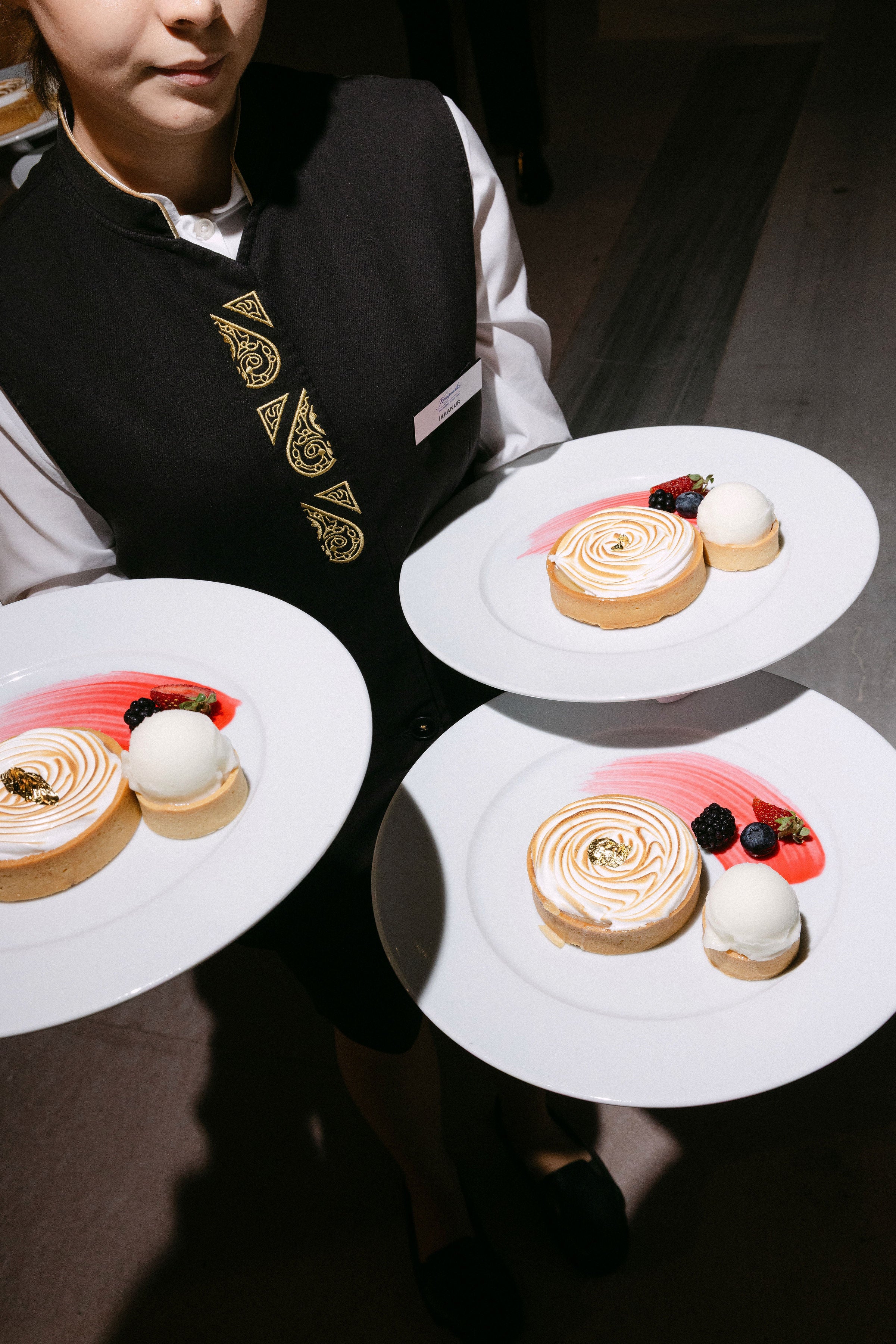 Person holding three plates of dessert