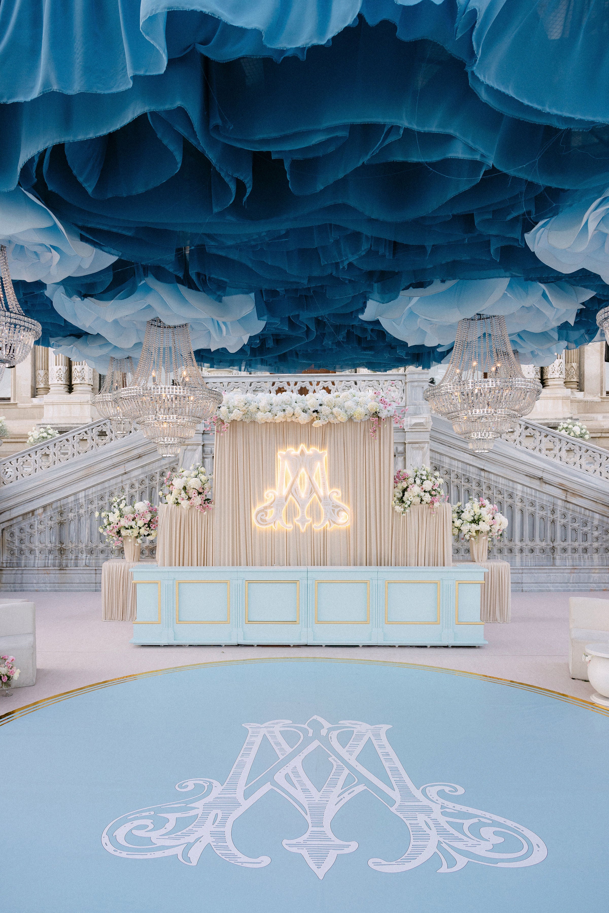 Decorative interior with blue ceiling and light blue floor, featuring floral arrangements and a large letter 'A'.