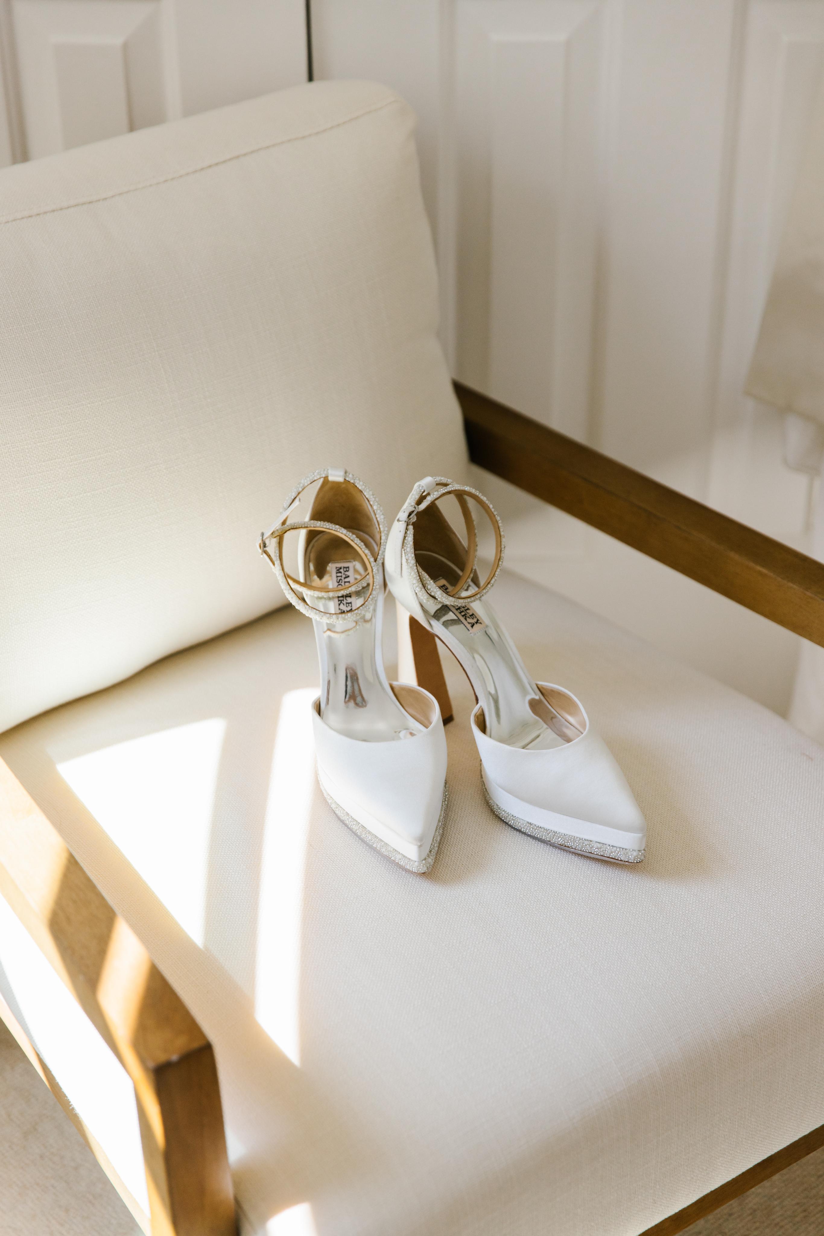 White high-heeled shoes on a white chair with gold accents