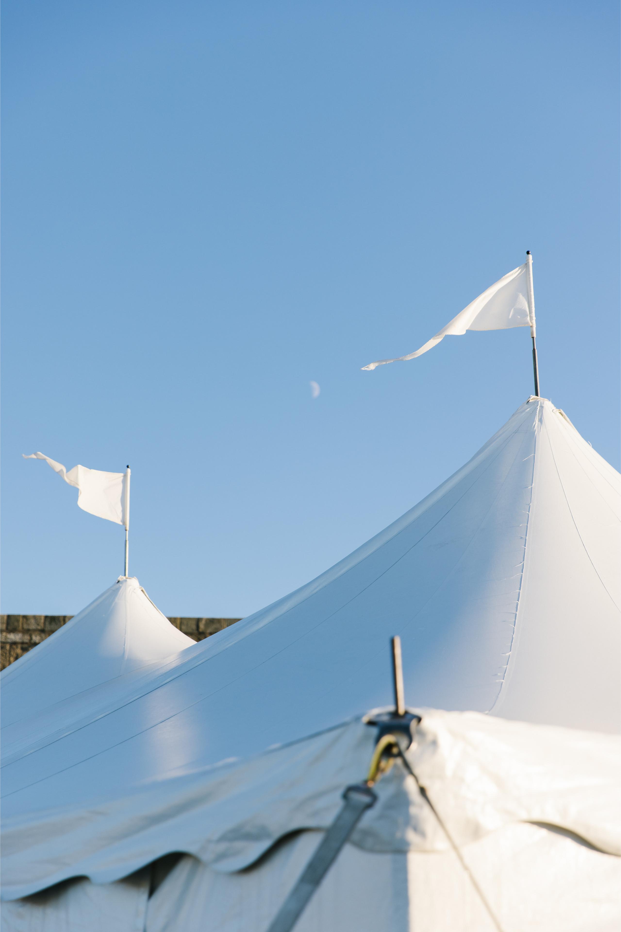White tents with flags against a clear blue sky