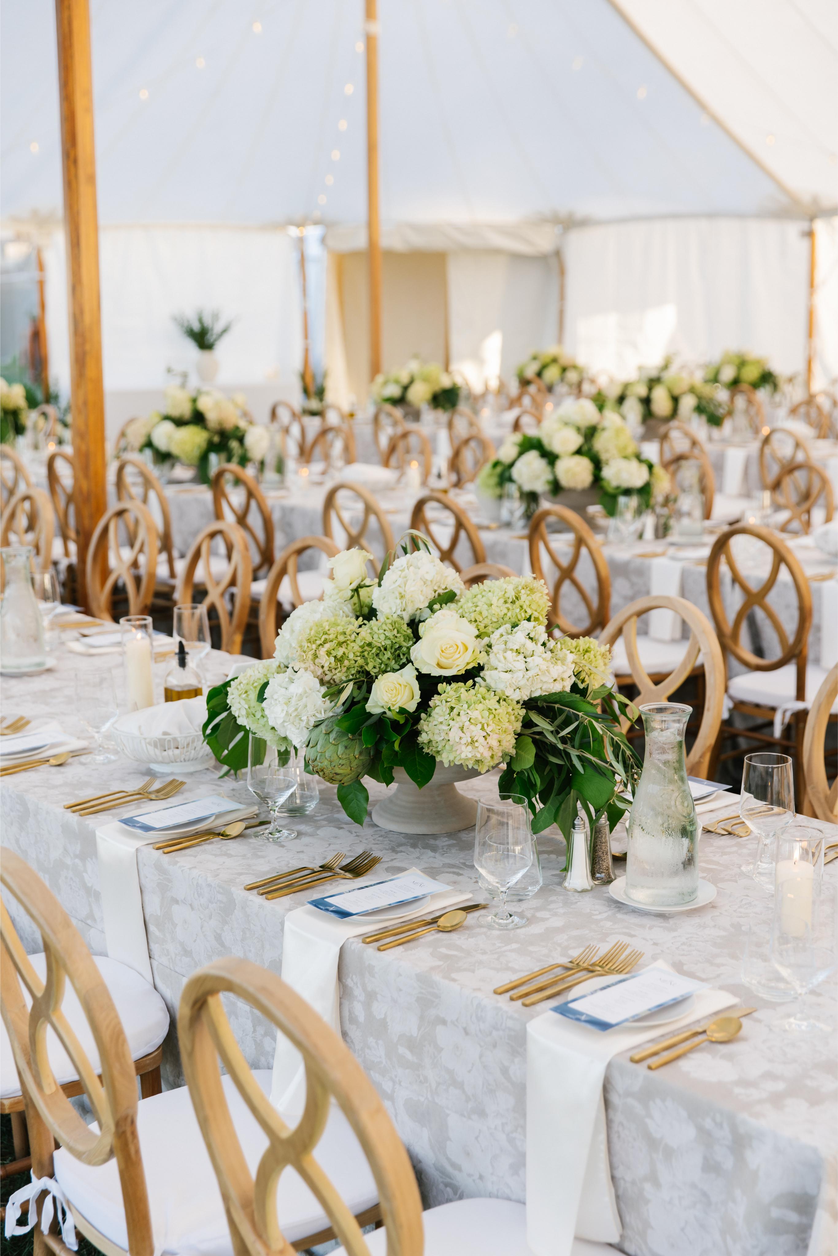Elegant wedding reception with tables set for dinner, featuring floral centerpieces and gold tableware.