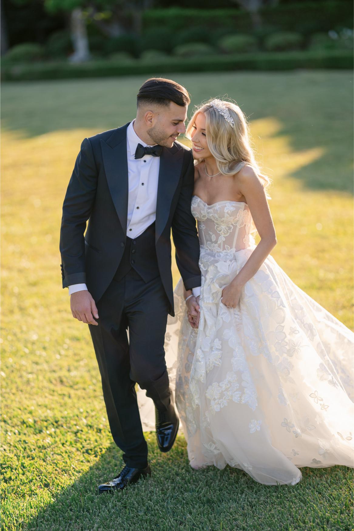 Groom in a tuxedo and our GL Bride Anaies in the Renee wedding dress standing on grass