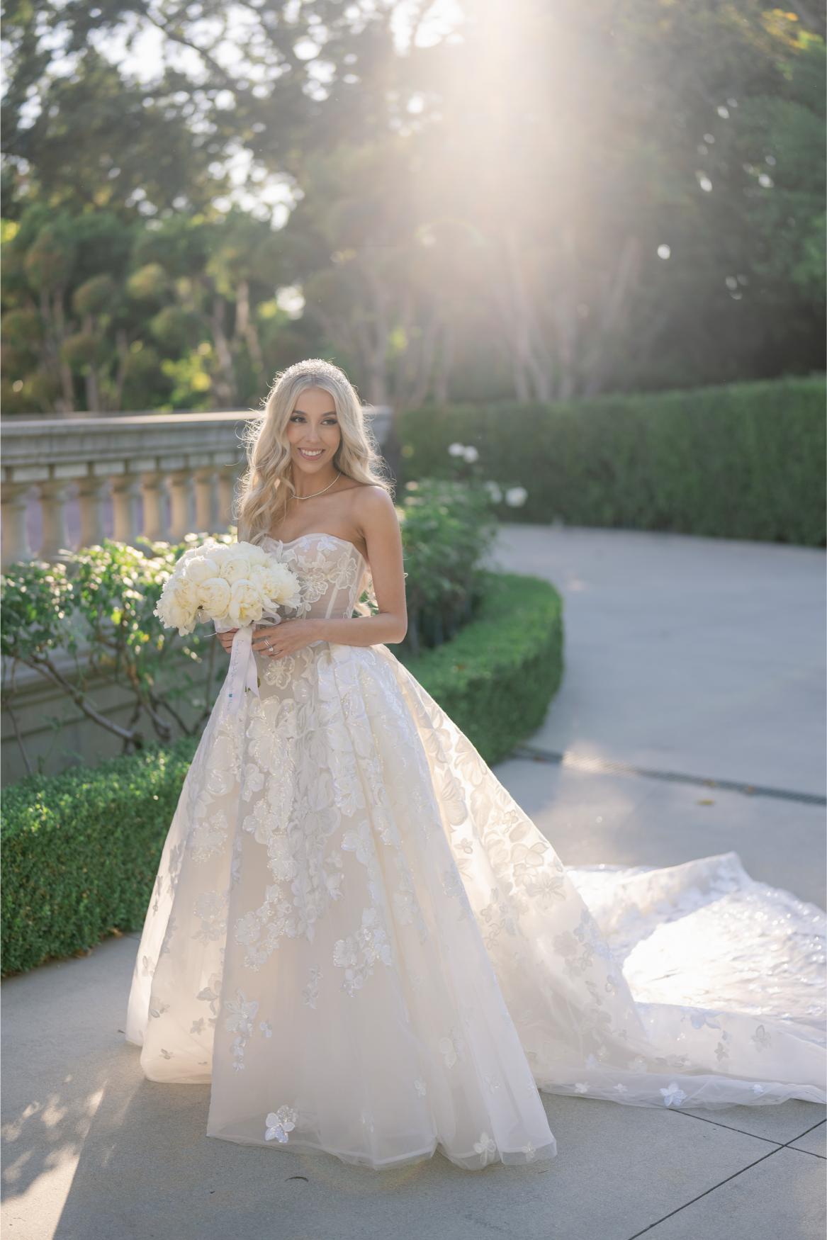 GL Bride Anaies in the Renee wedding dress holding flowers outdoors