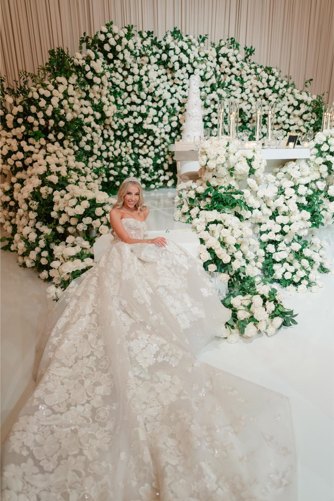 GL Bride Anaies in the Renee wedding dress from Galia Lahav Rise Collection  surrounded by white flowers and greenery.