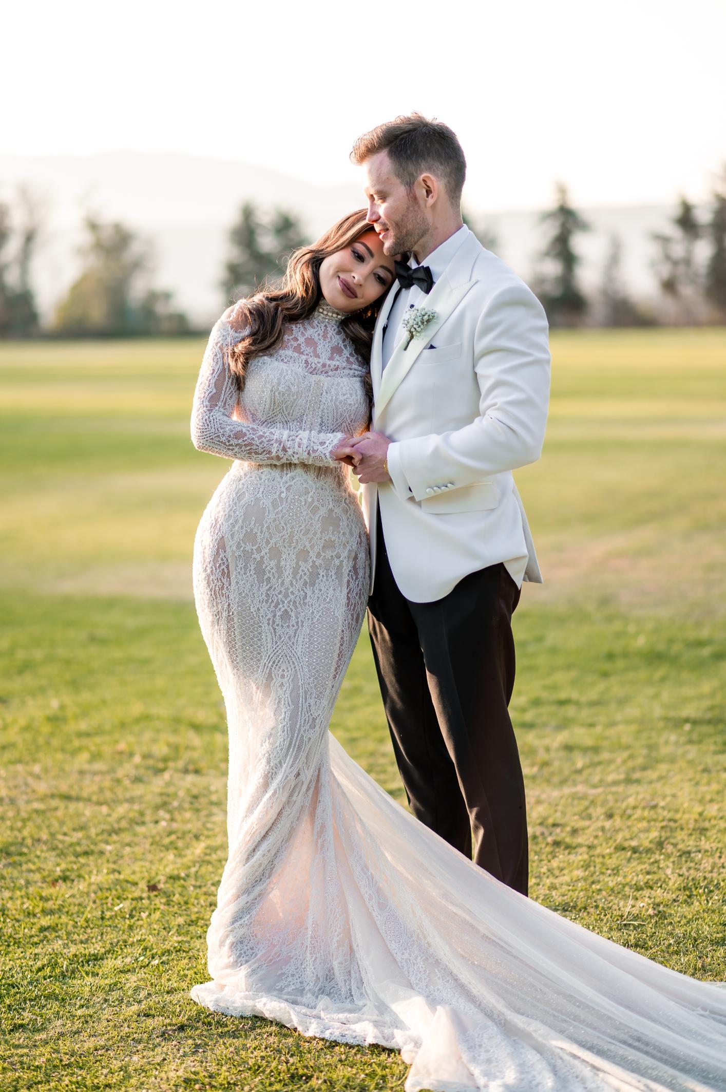 GL Bride Betty Luna in our Élysée, embracing her husband in an open garden setting 