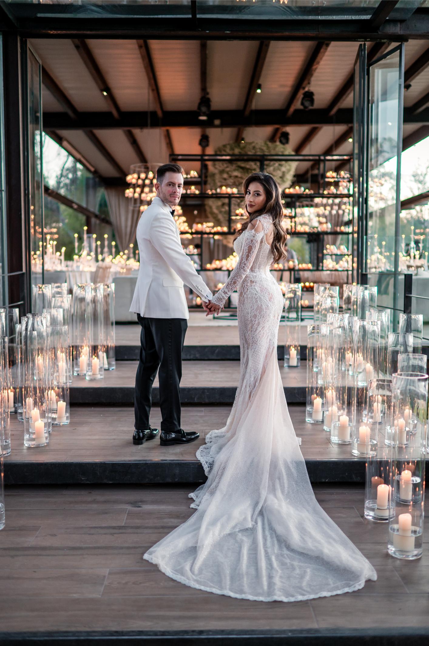 GL Bride Betty Luna in our Élysée standing next to her husband, with lit candles surrounding them