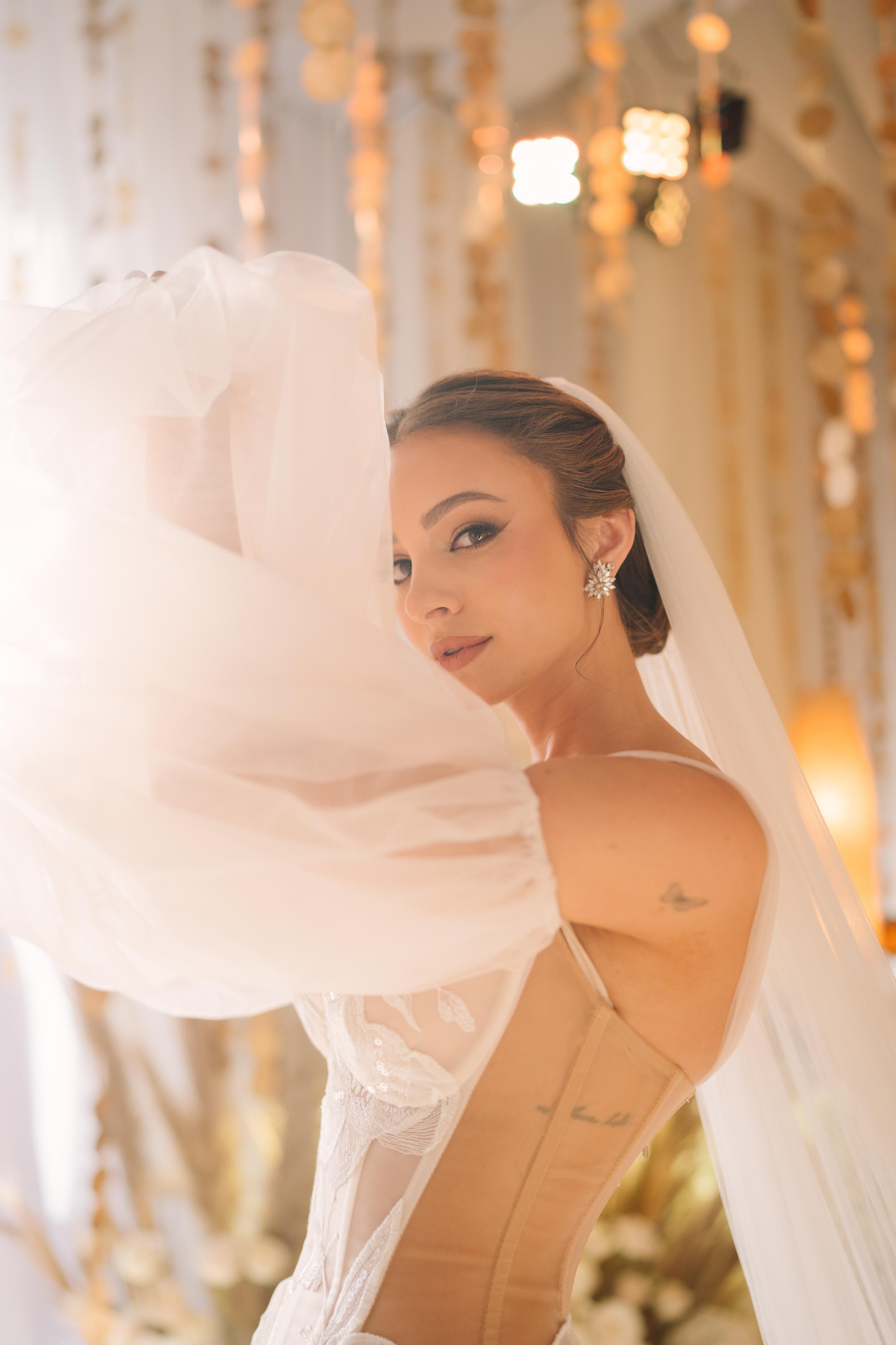 GL Bride Carina wearing the Evelyn wedding with a veil in an elegant indoor setting.