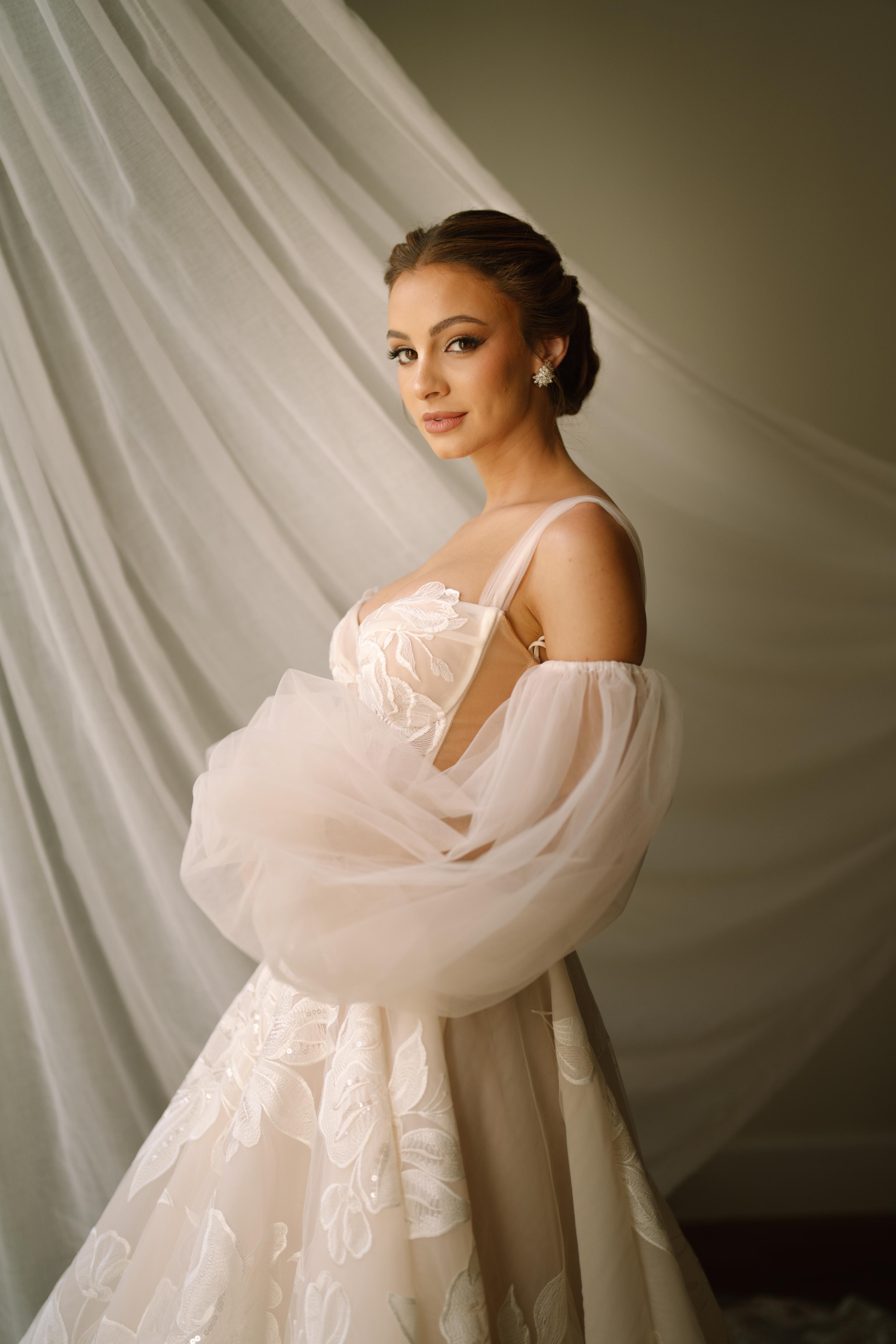 GL Bride Carina wearing the Evelyn wedding dress standing against a draped fabric background