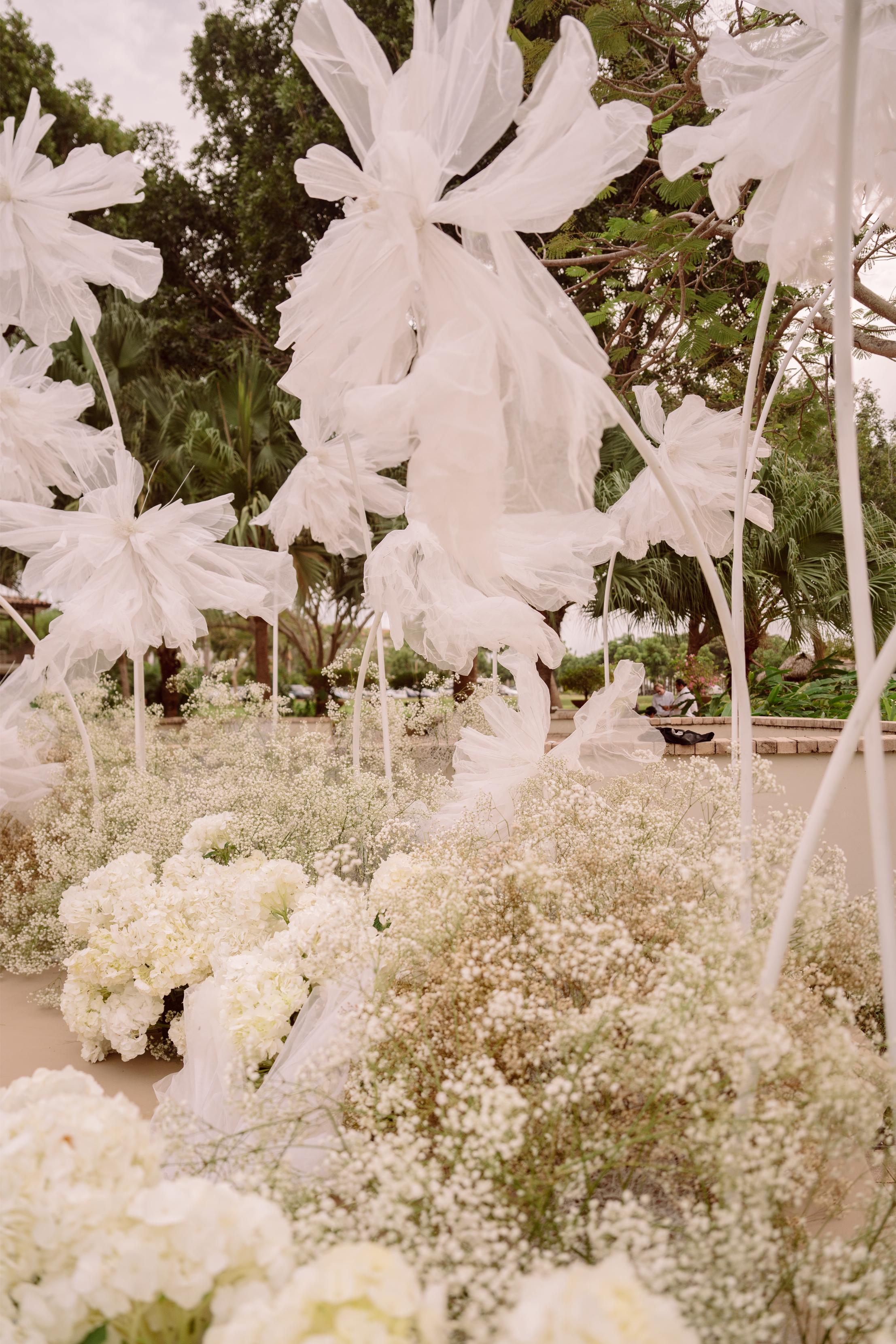 Decorative floral arrangement with white flowers and greenery in an outdoor setting.