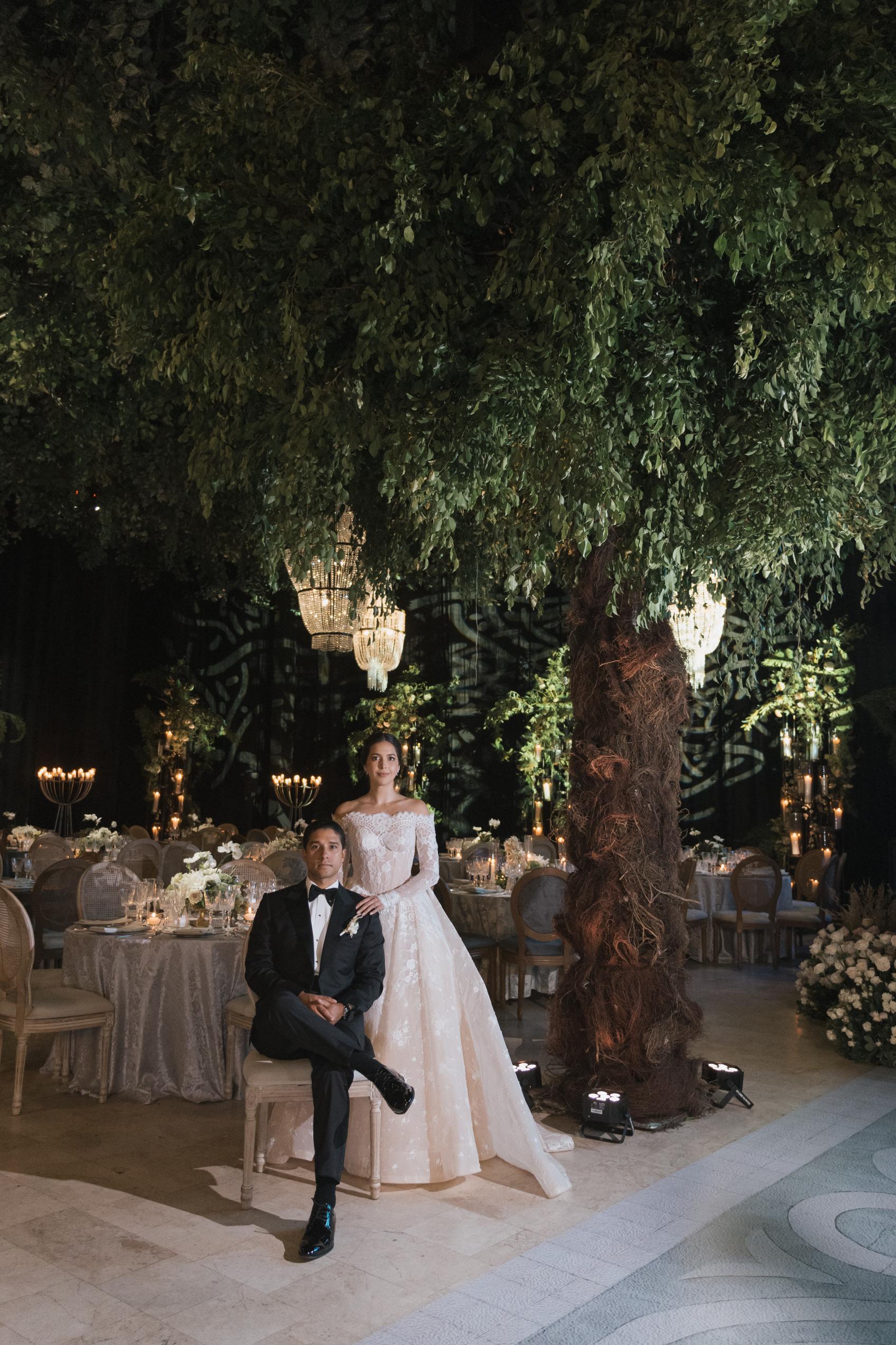 Couple posing in a decorated outdoor setting with chandeliers and tables.