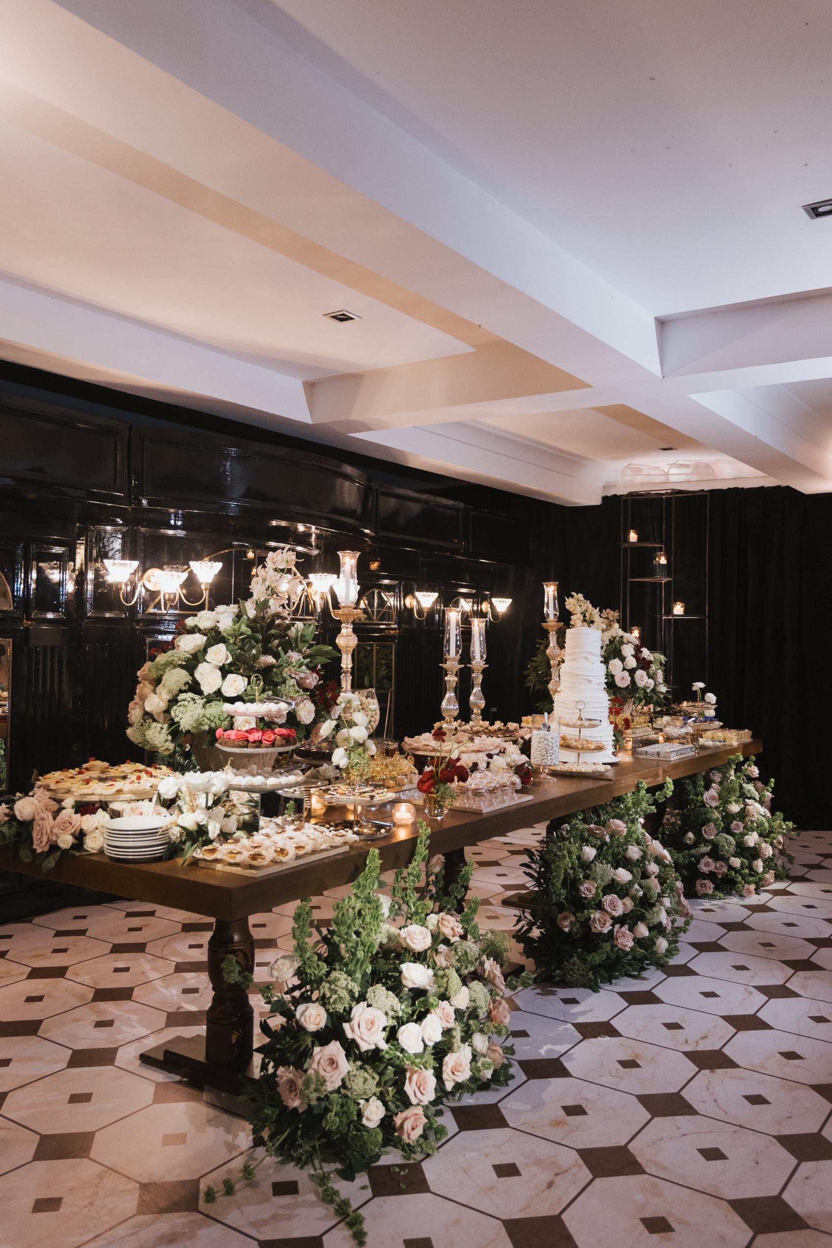 Decorative table setup with flowers and a cake in an elegant room.
