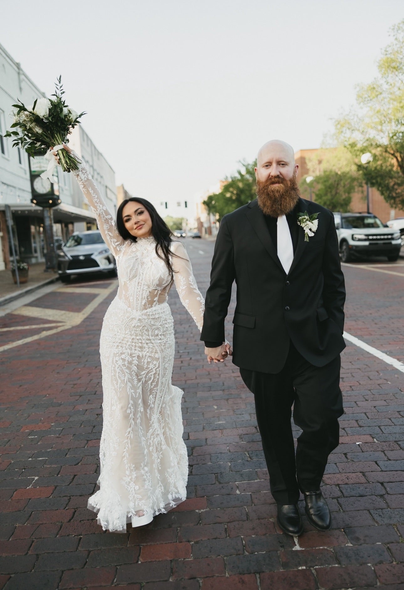 Wedding couple holding hands on a city street.