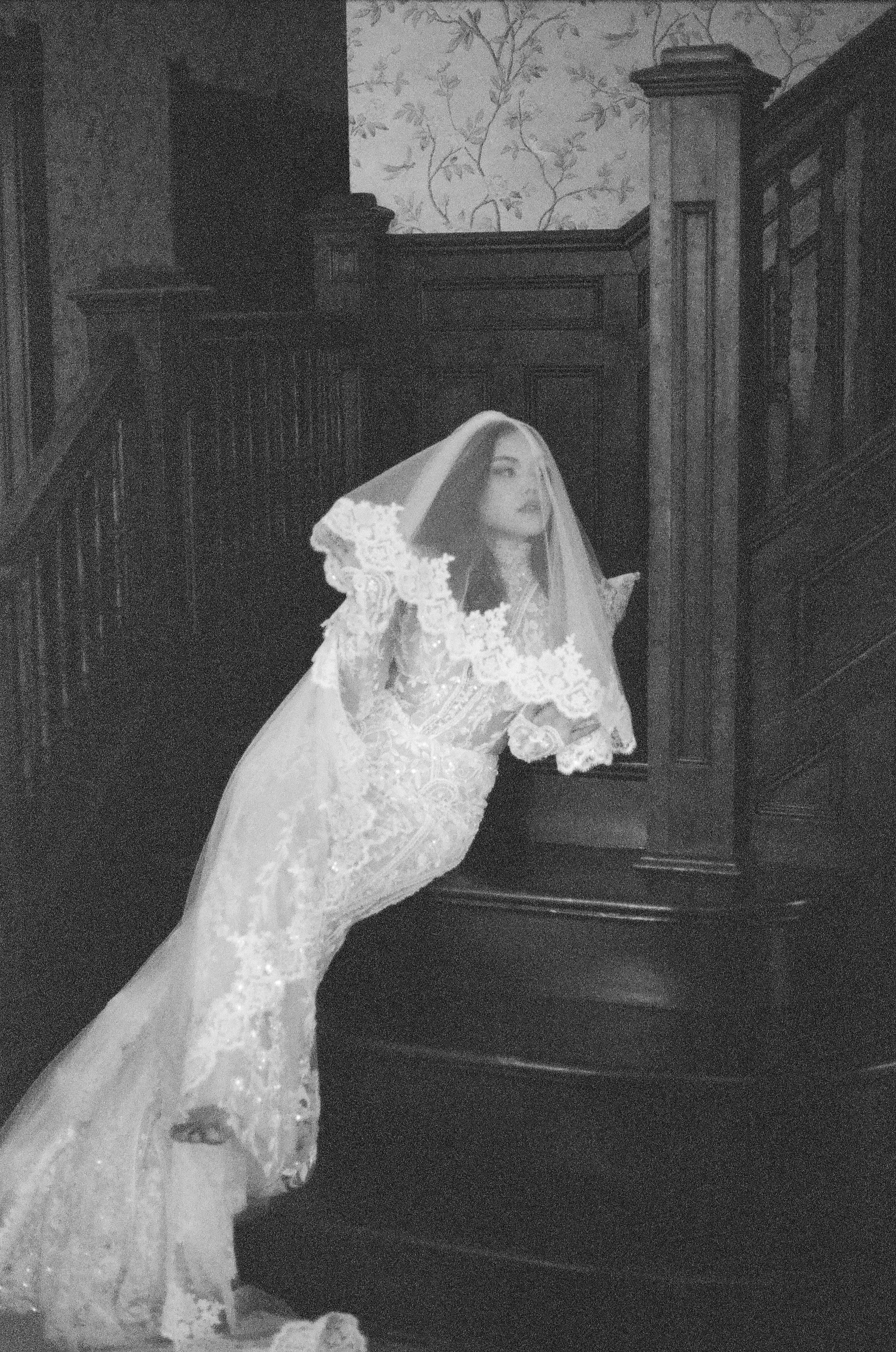 Woman in a wedding dress and veil standing on a staircase
