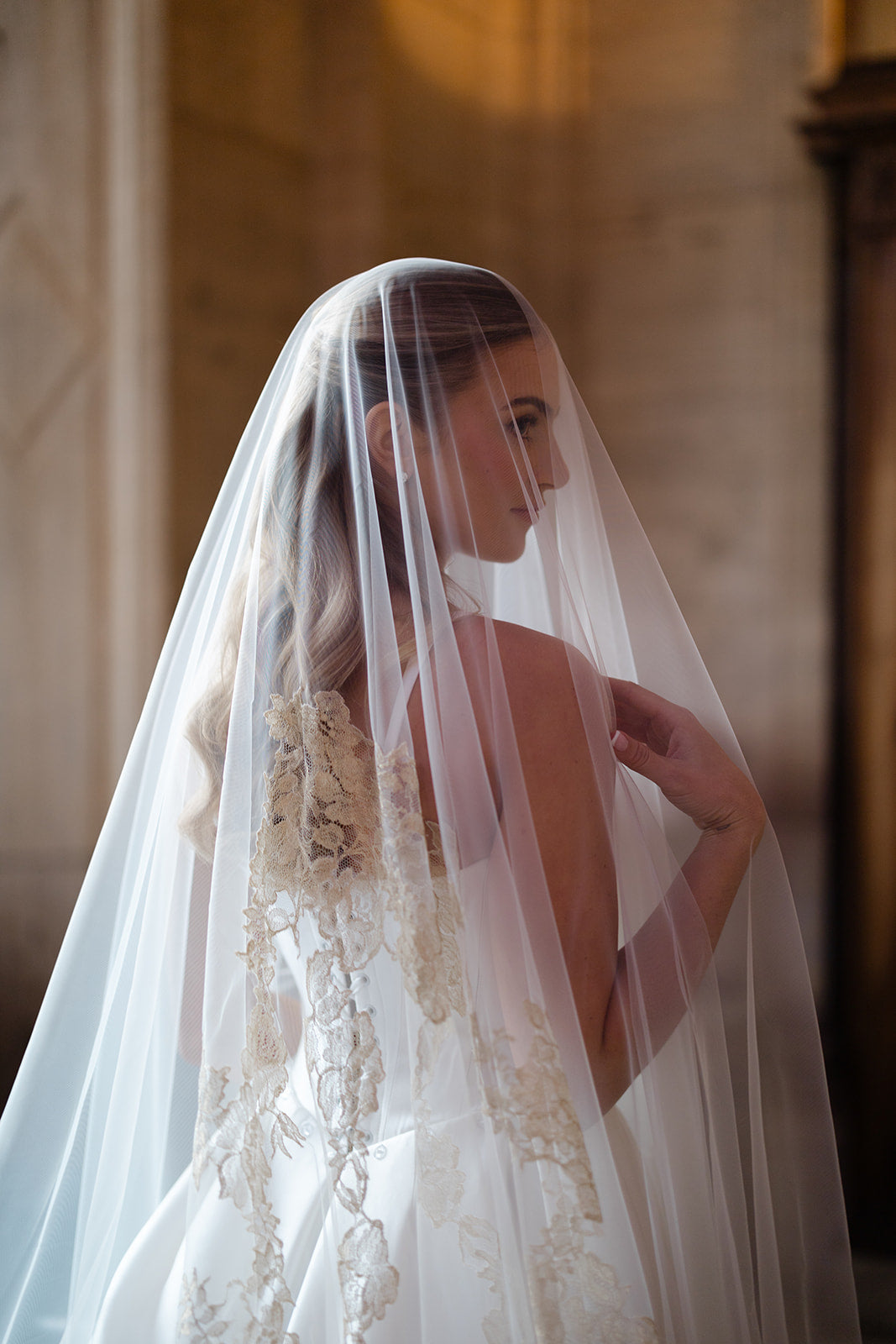 Bride wearing a lace wedding dress and veil indoors