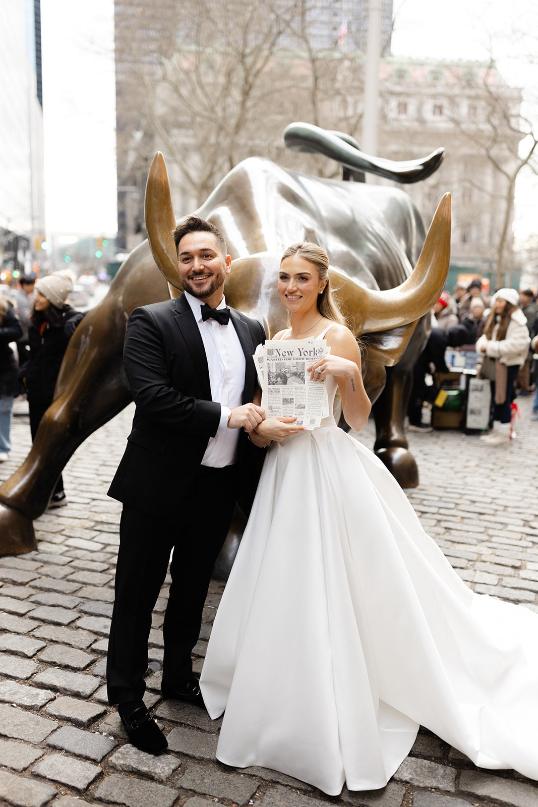 GL Bride Eliza in our Dove with her husband standing next to the Charging Bull statue in New York City.