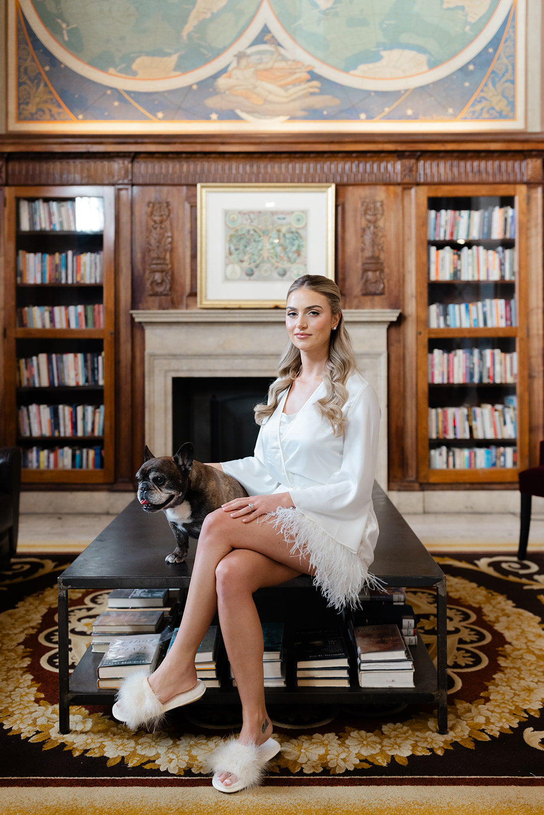 GL Bride Eliza in a white dress sitting on a bench with her dog in a library setting