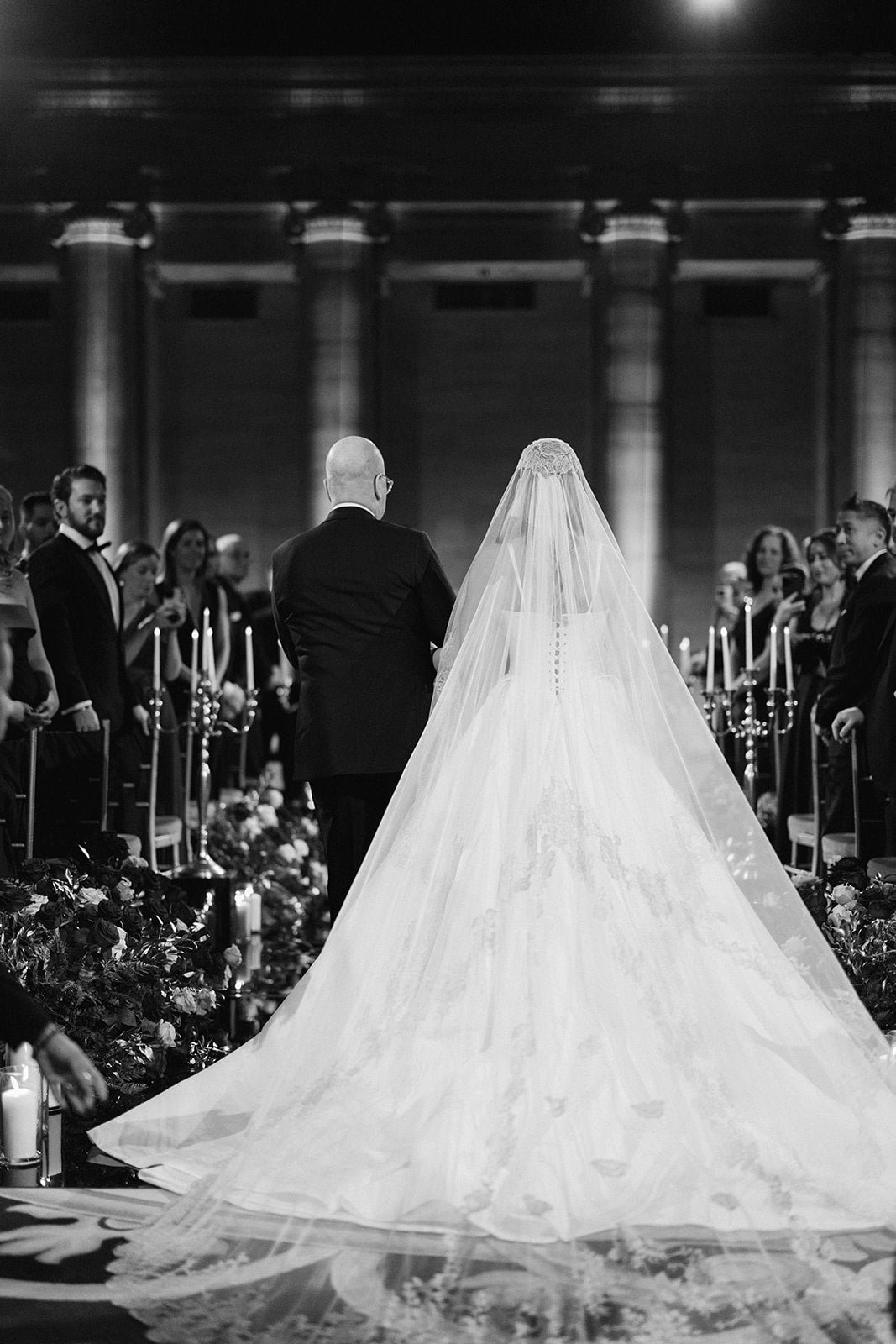 Black and white photo of a wedding ceremony with a long veil.
