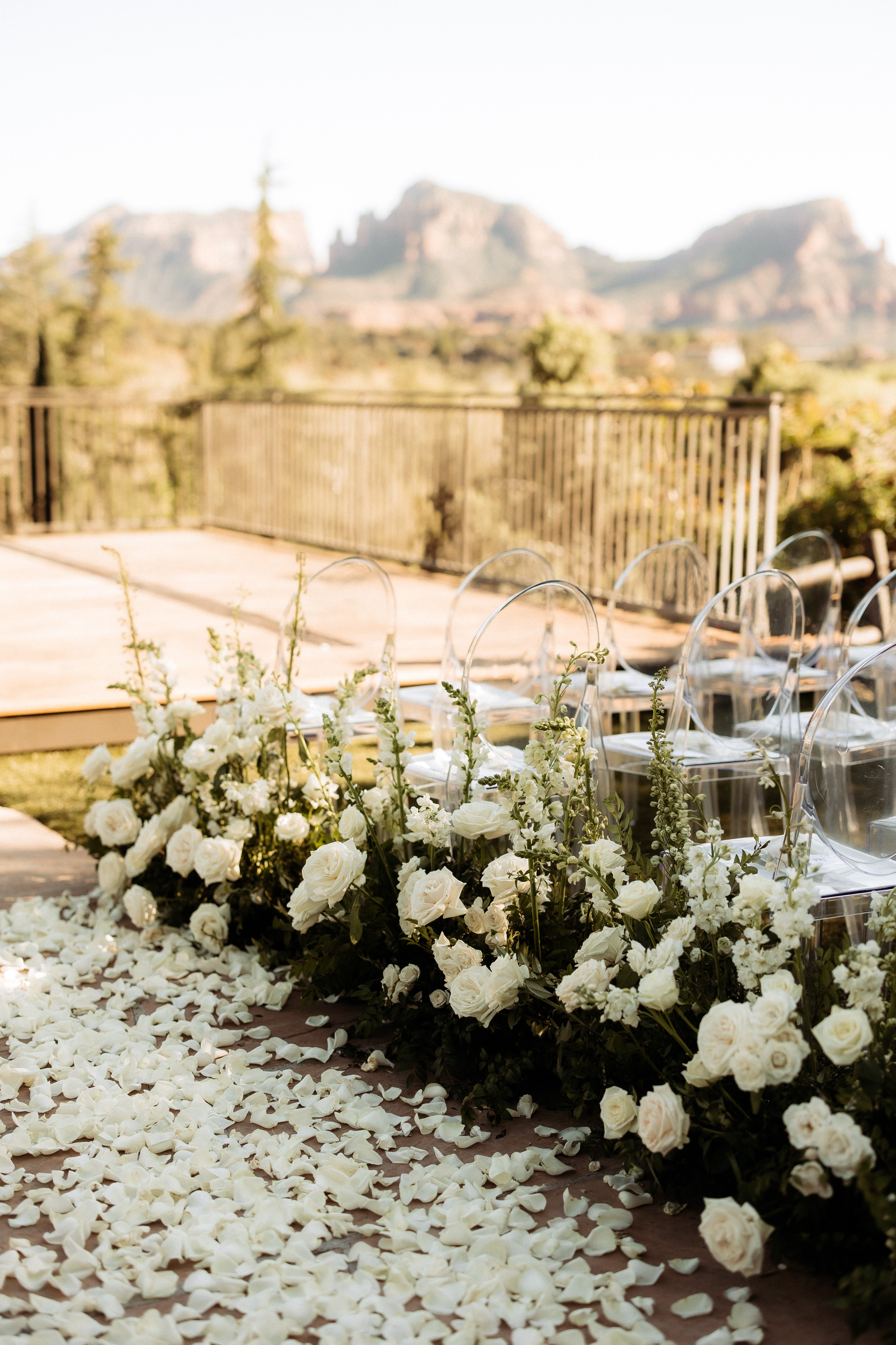 Decorative floral arrangement with white flowers and greenery on a table outdoors.